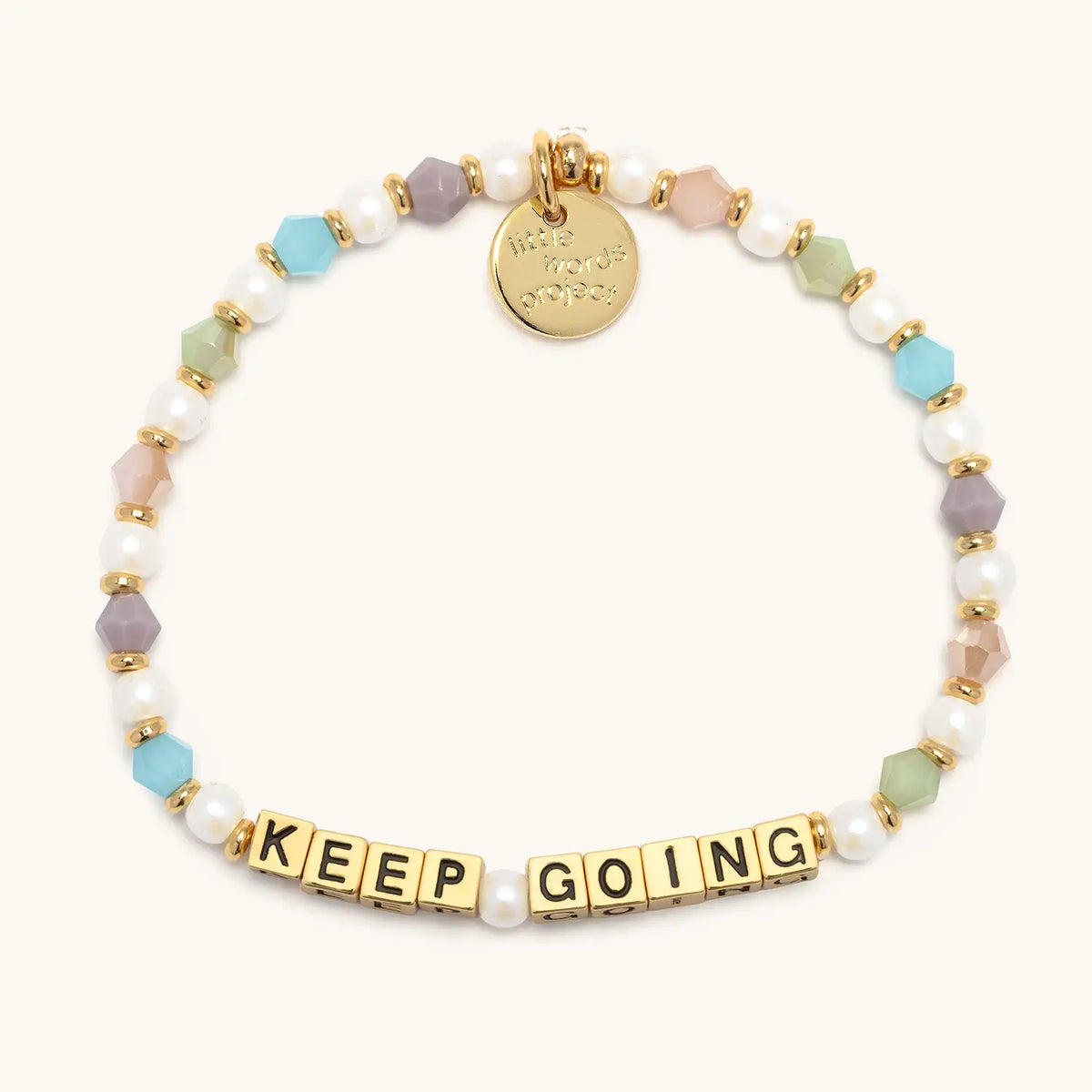 Keep Going bracelet with gold letter beads from the Good Things Ahead Bracelet Set, flat-lay on cream background