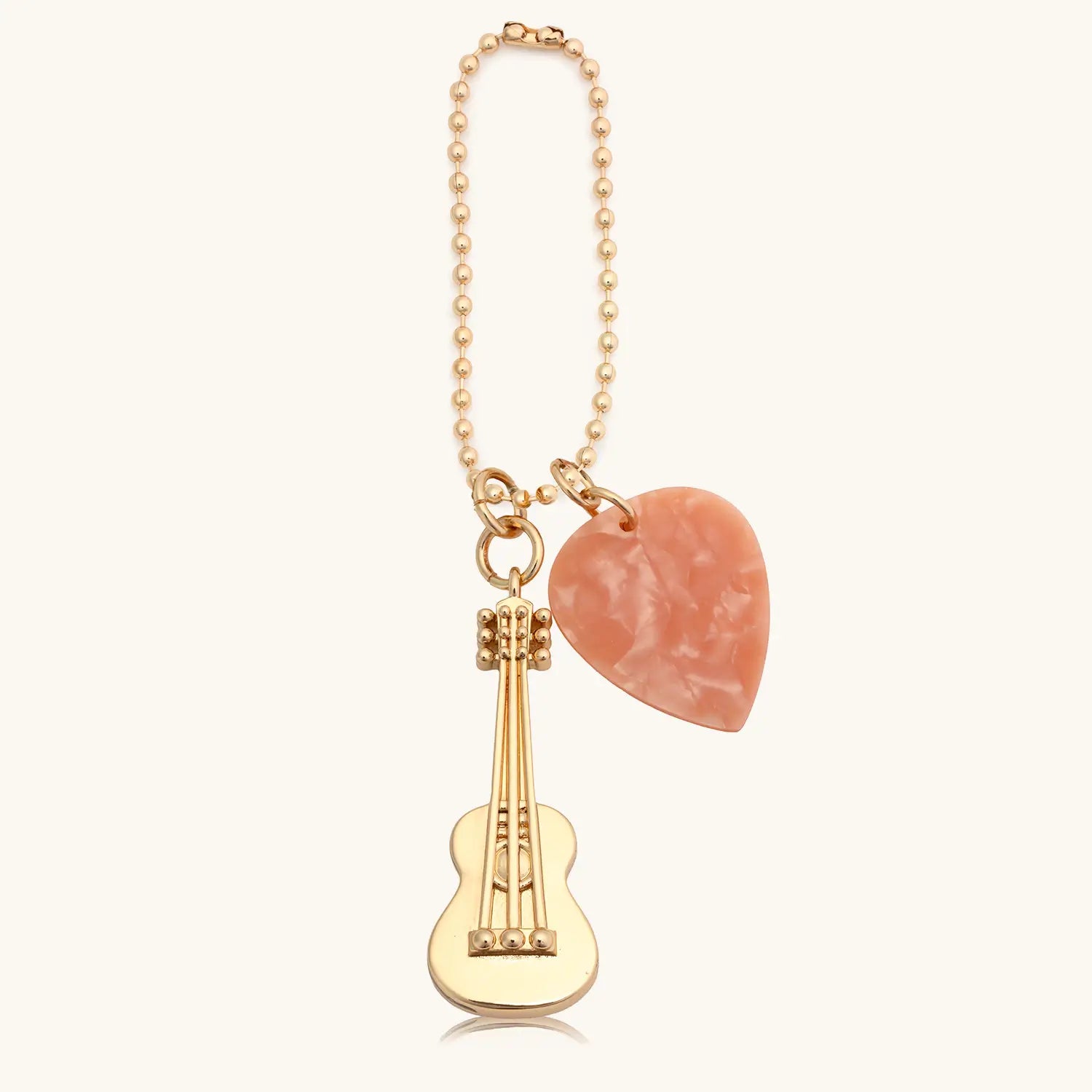 Bag charm with guitar and peach colored guitar pick on a white background