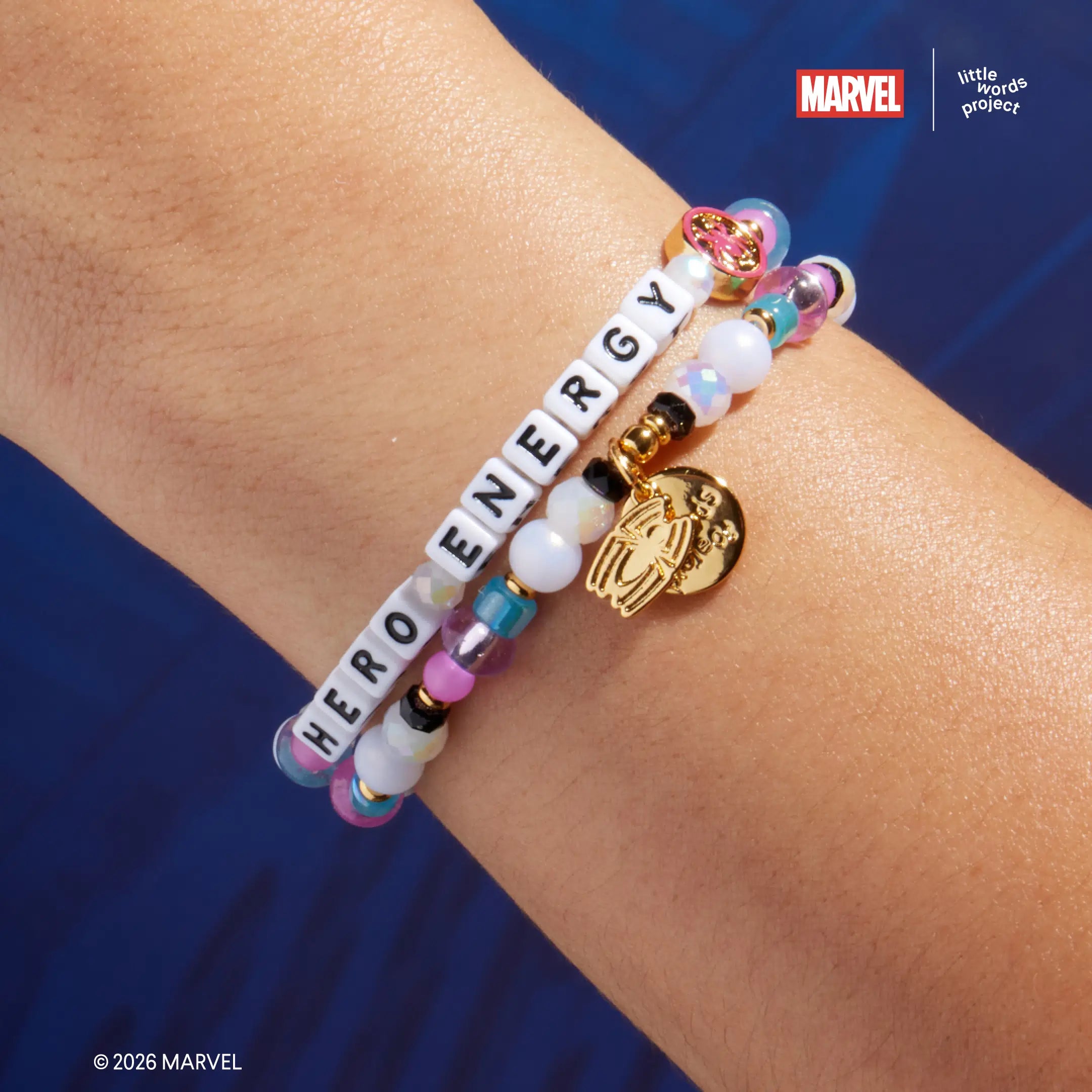 Hero Energy bracelet from Marvel's Spider-Man collection worn on wrist, on-model close-up showing white, pink, and blue beads with gold Spider-Man casted bead