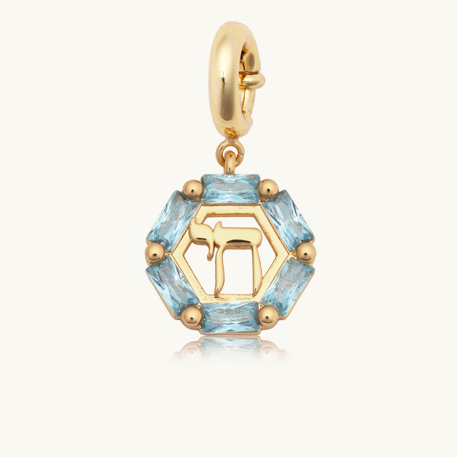 Gold charm with blue gemstones on a white background