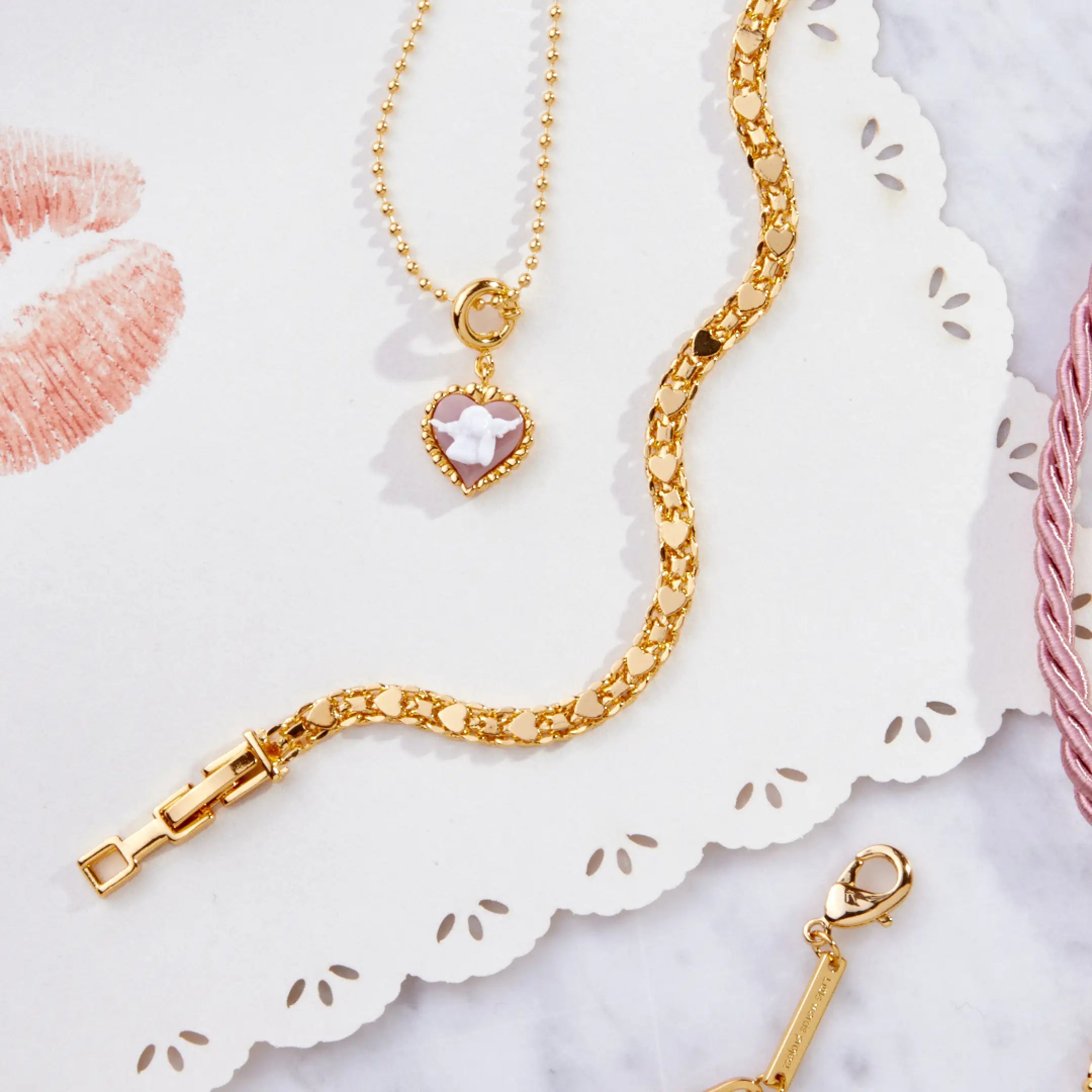 Gold bracelet with a heart-shaped charm on a decorative white surface