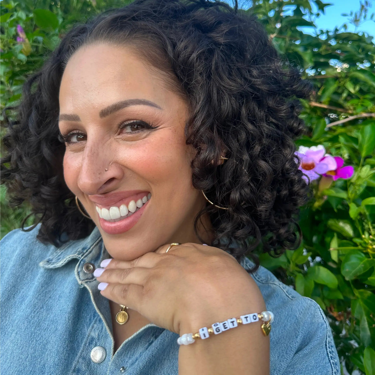 Jeslyn Gorman smiling in a denim shirt wearing her I Get To bracelet, on-model portrait outdoors