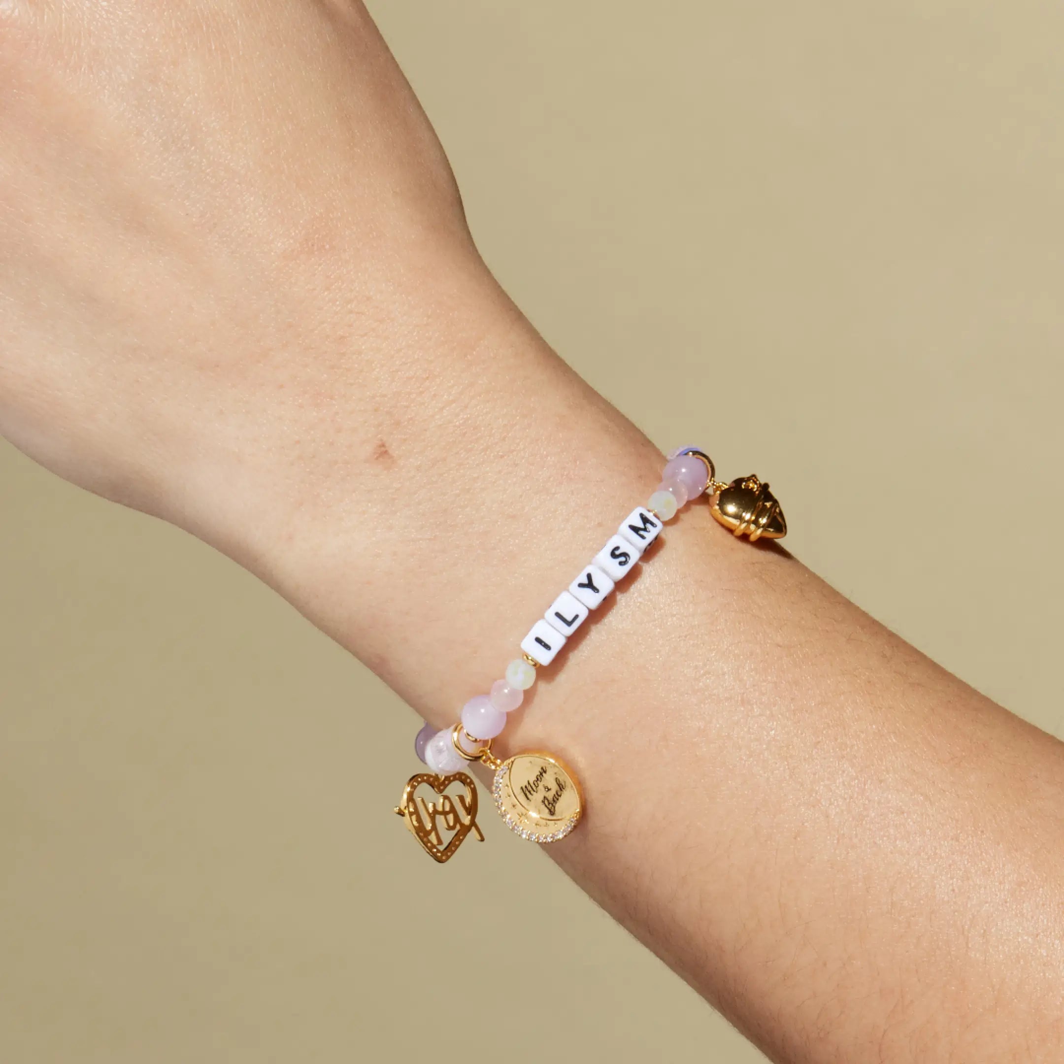 Bracelet with charms on a wrist against a beige background