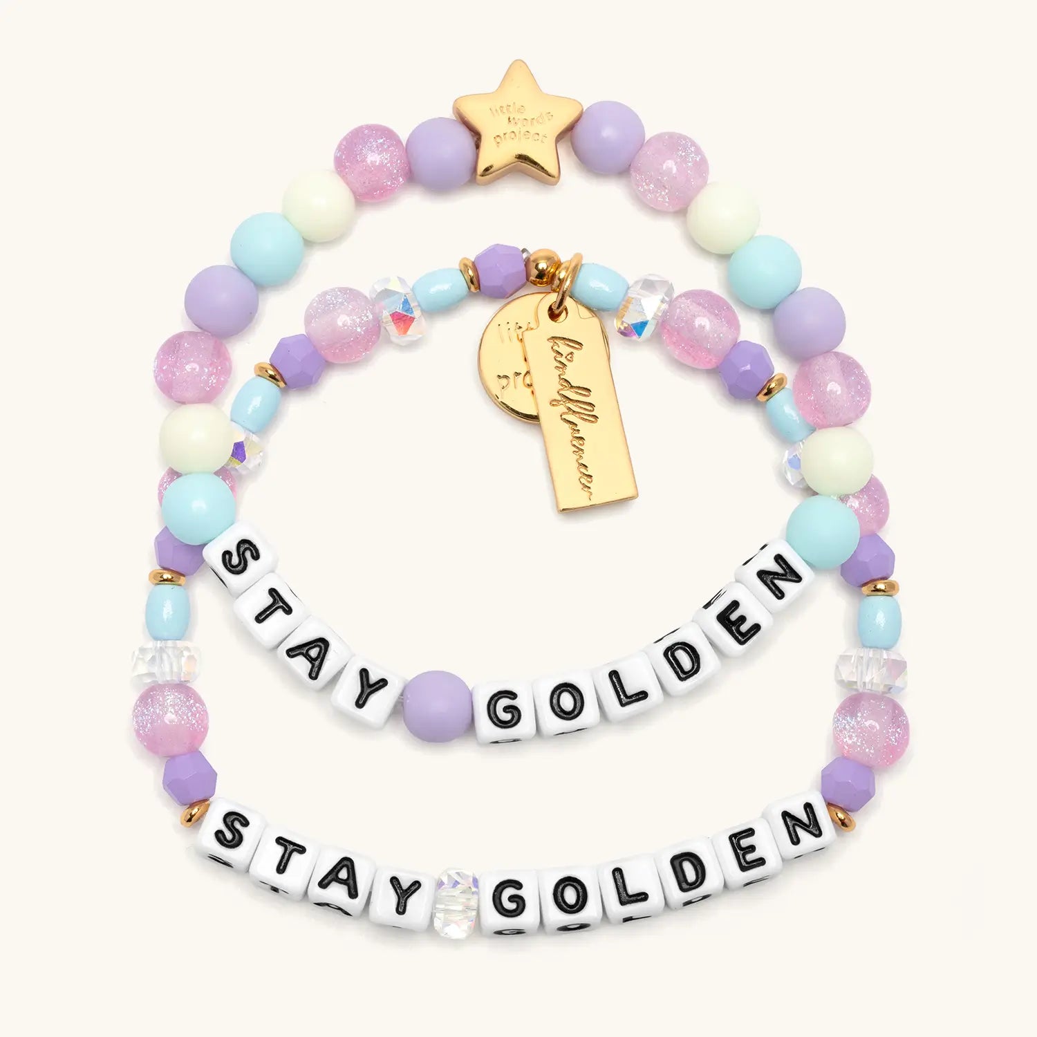 Stay Golden Bracelet Set Rylee Ta with adult bracelet in white letter beads and kids bracelet in white letter beads, lavender crystal, light blue and cream beads with gold star charms, flat lay