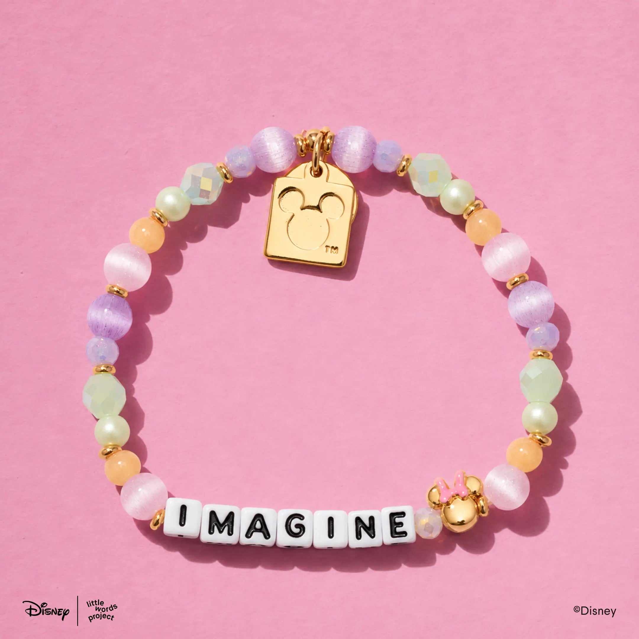 Imagine Disney Mickey and Friends bracelet flat lay on pink with pastel beads and a gold plated casted Mickey Mouse tag charm