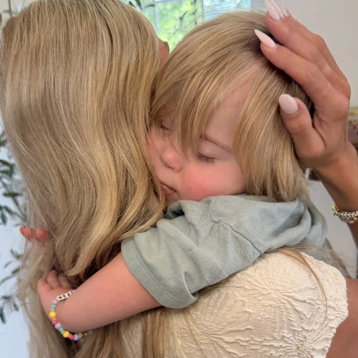 Kirstin Czernek hugging her young son, who wears a rainbow beaded Little Words Project bracelet, lifestyle