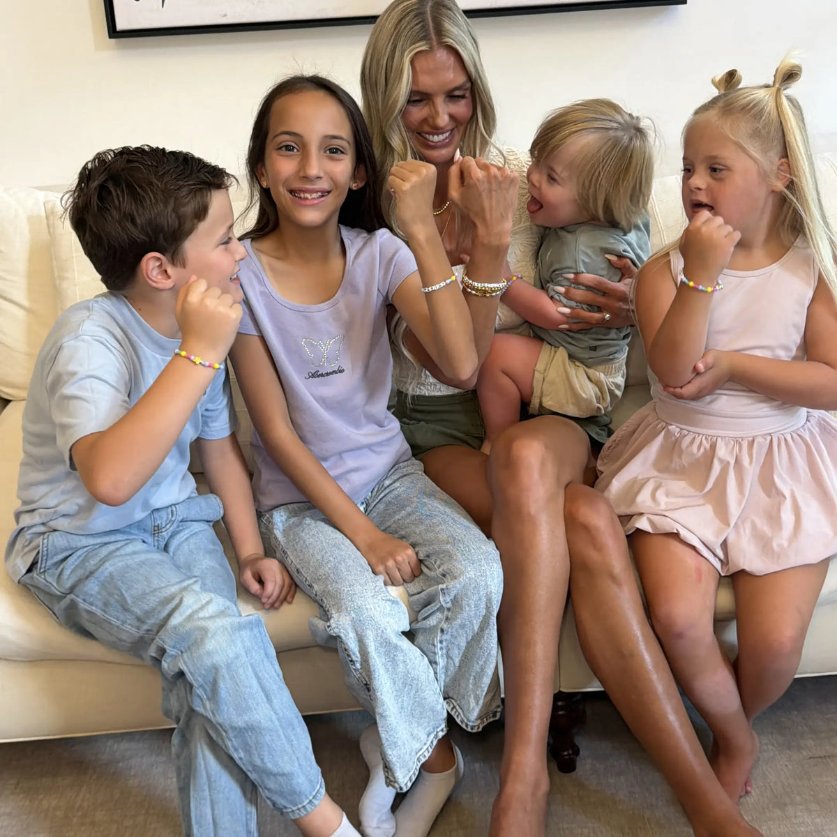 Kirstin Czernek with her four children on a cream sofa, each wearing Little Words Project bracelets, lifestyle