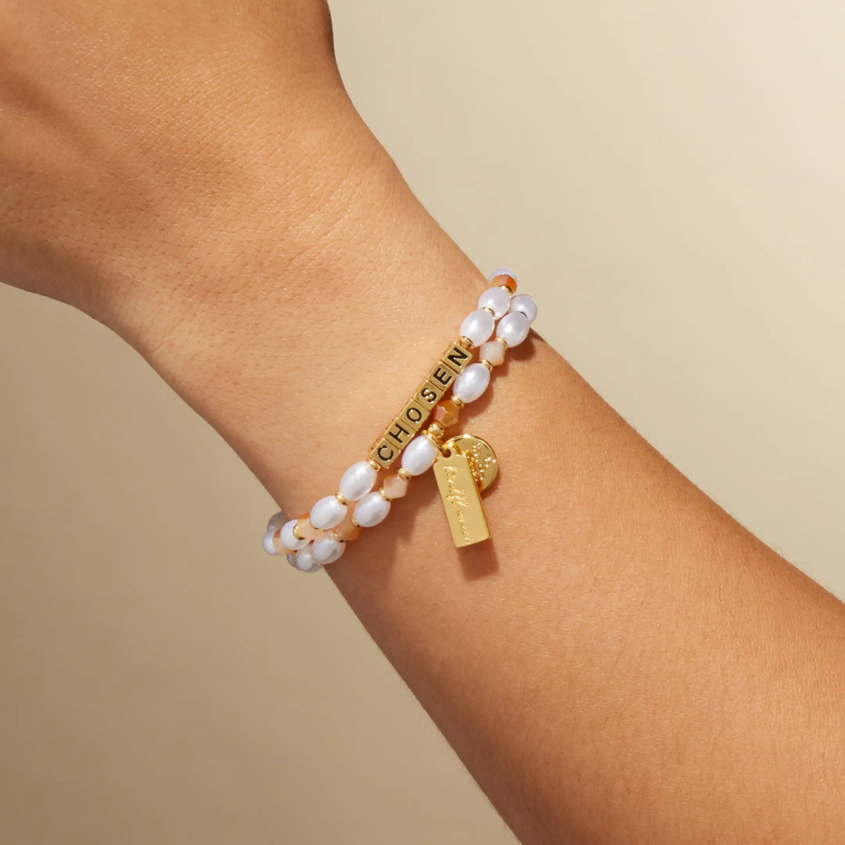 Chosen bracelet by Kirstin Czernek on-model on wrist, gold letter beads with white faux pearls and champagne crystals