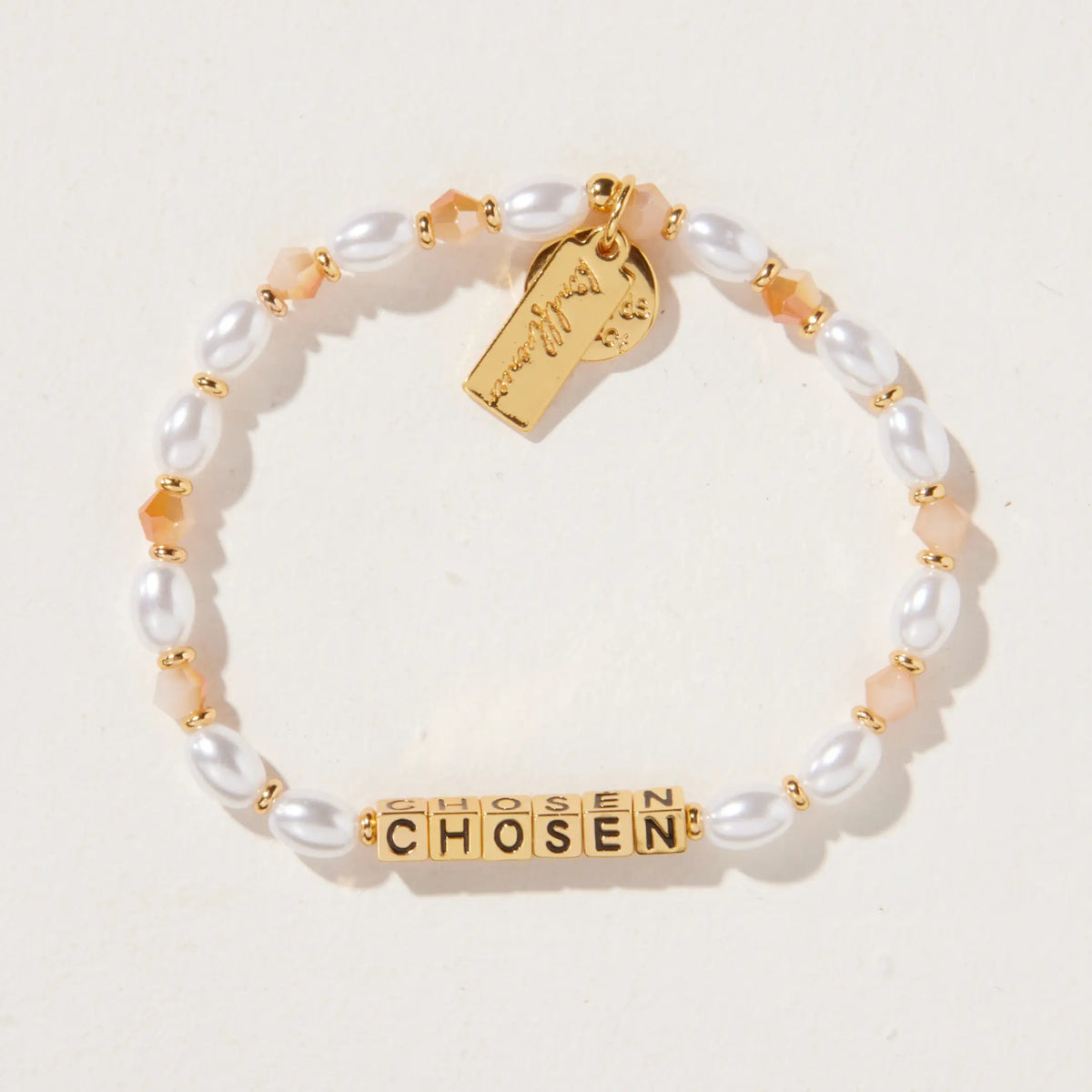 Chosen bracelet by Kirstin Czernek, gold letter beads with white faux pearls and champagne crystals with gold accents, detail flat-lay on light background