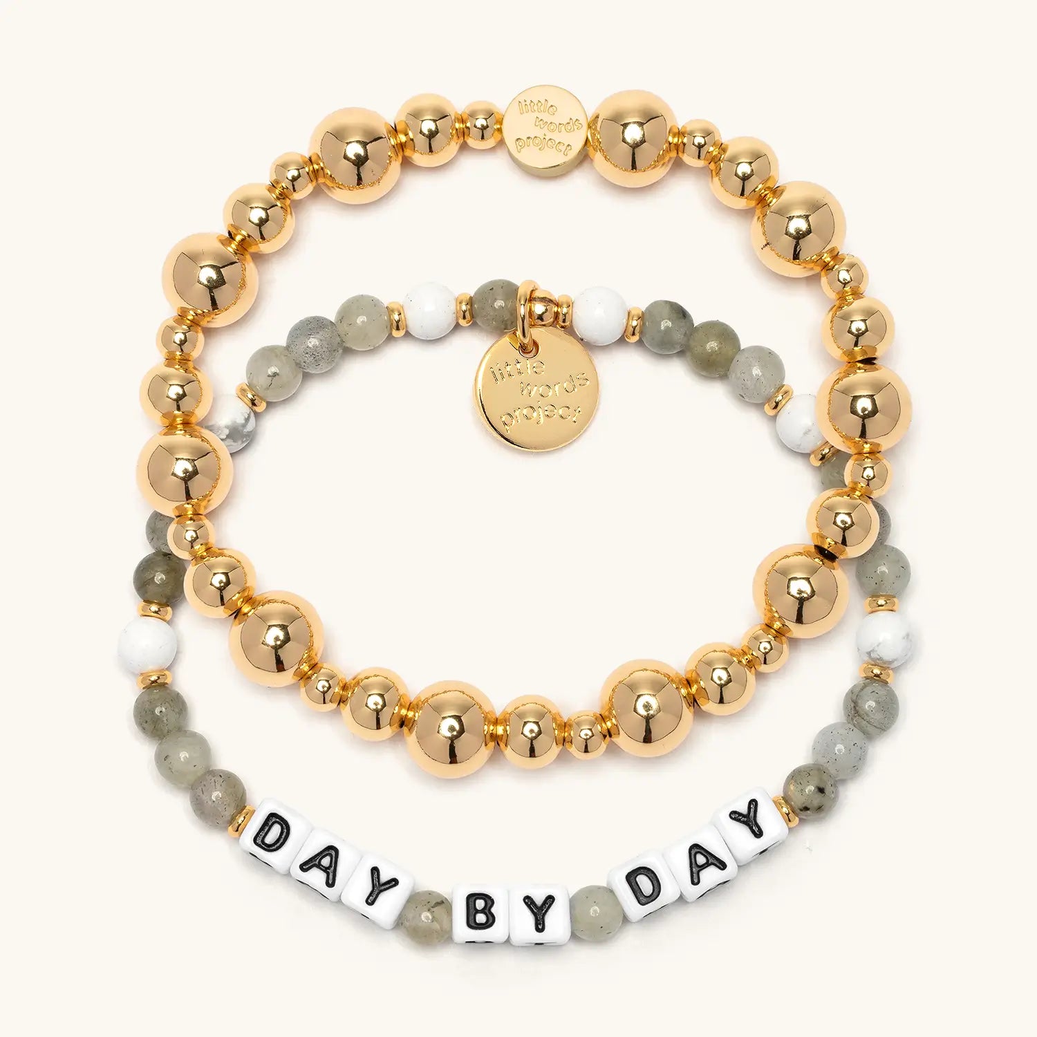 Day by Day Bracelet Set from the Project HEAL giveback collection, the gold plated Gold Bubbles bracelet base stacked above the Day by Day bracelet in grey and white semi-precious stone beads