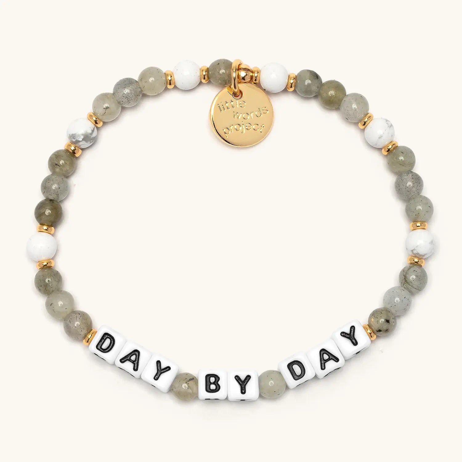 Day by Day bracelet from the Project HEAL giveback collection, grey and white semi-precious stone beads with gold accents, black and white letter beads spelling DAY BY DAY, and a gold Little Words Project logo tag