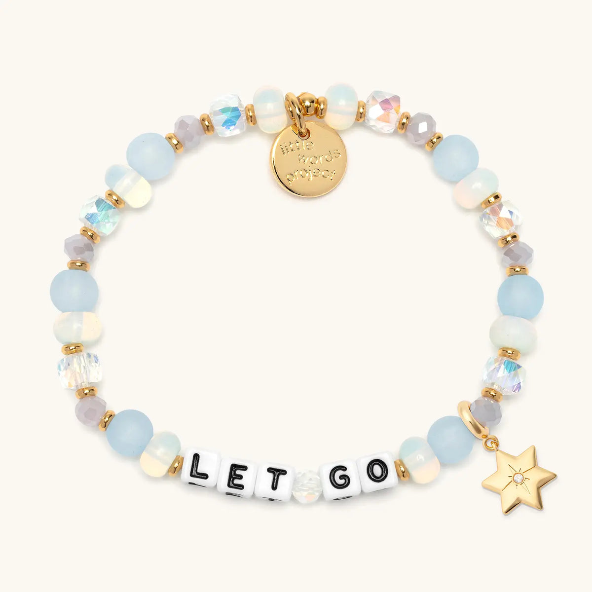 Let Go bracelet in the Marshmellow bead pattern with white letter beads, gold puffy Star of David charm with a clear CZ stone, flat-lay on cream background