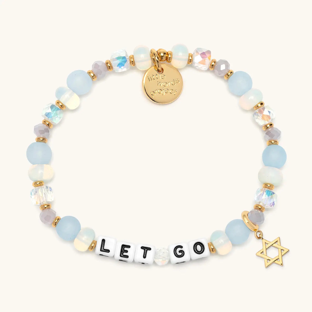 Let Go bracelet in the Marshmellow bead pattern with white letter beads, gold Star of David charm, flat-lay on cream background
