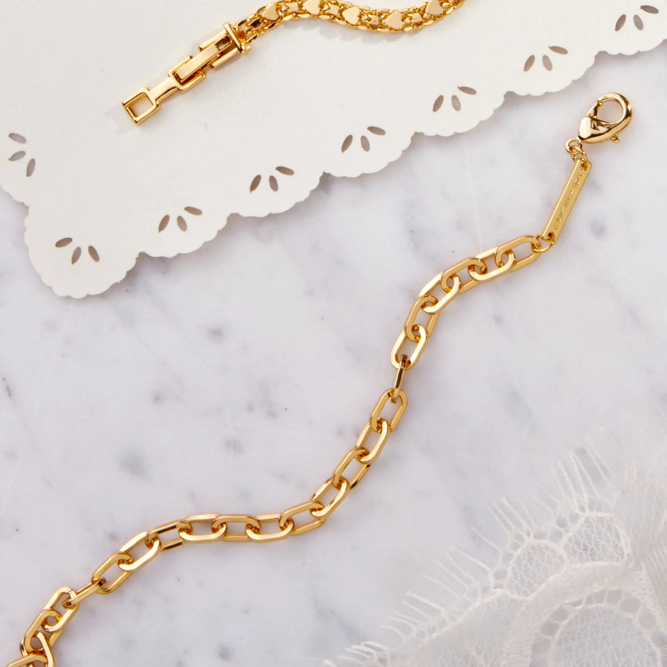 Gold chain bracelet on a marble surface with decorative paper