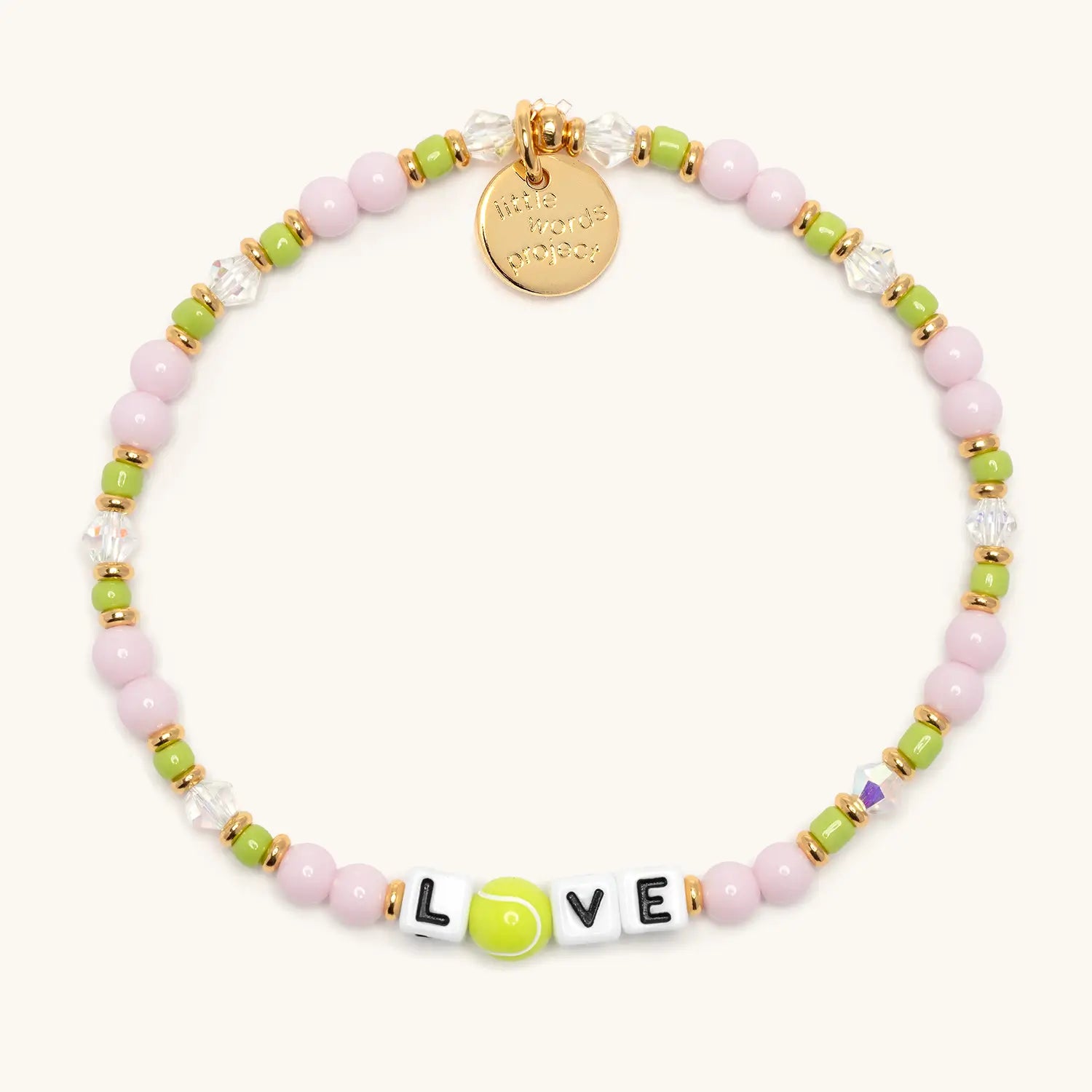 Love tennis bracelet flat lay with pink and green beads, clear crystals, gold accents, and letter beads spelling LOVE with a tennis ball bead as the O