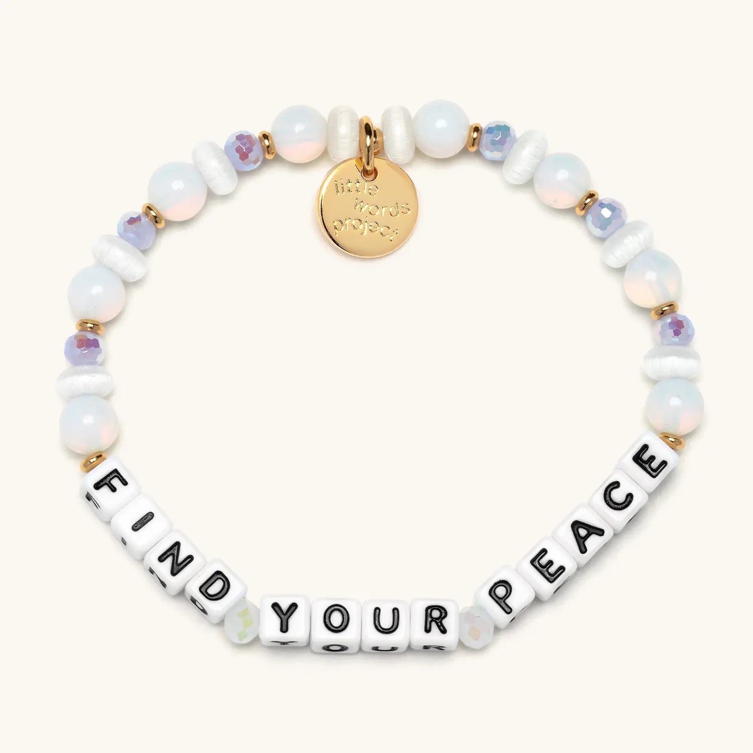 A beaded bracelet spelling FIND YOUR PEACE in white square letter beads with black lettering, accented with irregular white freshwater pearl beads, iridescent opal beads, small lavender crystal beads, and gold spacer beads. A small gold circular charm hangs from the top of the bracelet.