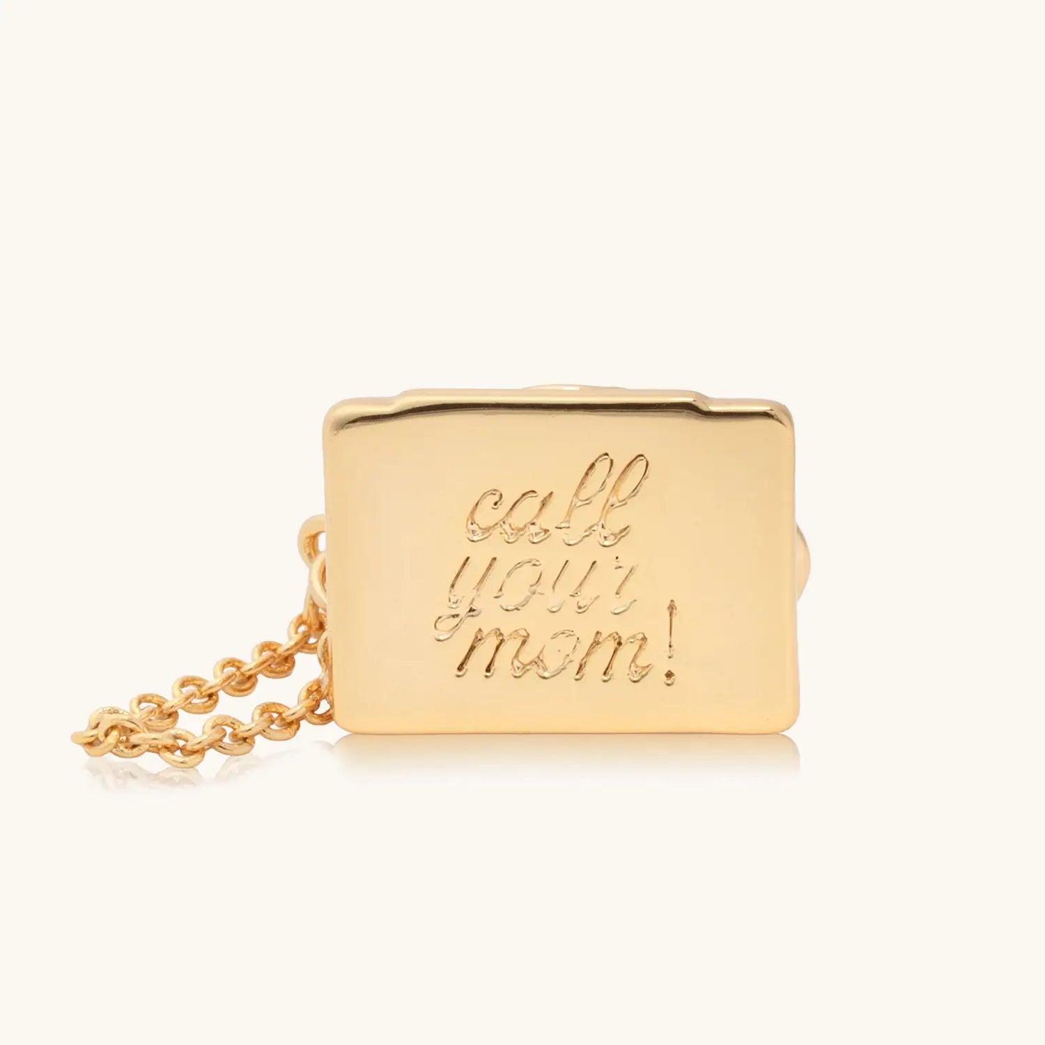 A small gold rectangular minaudière clutch bag with the phrase "call your mom!" engraved in cursive script on the front, attached to a gold chain strap.