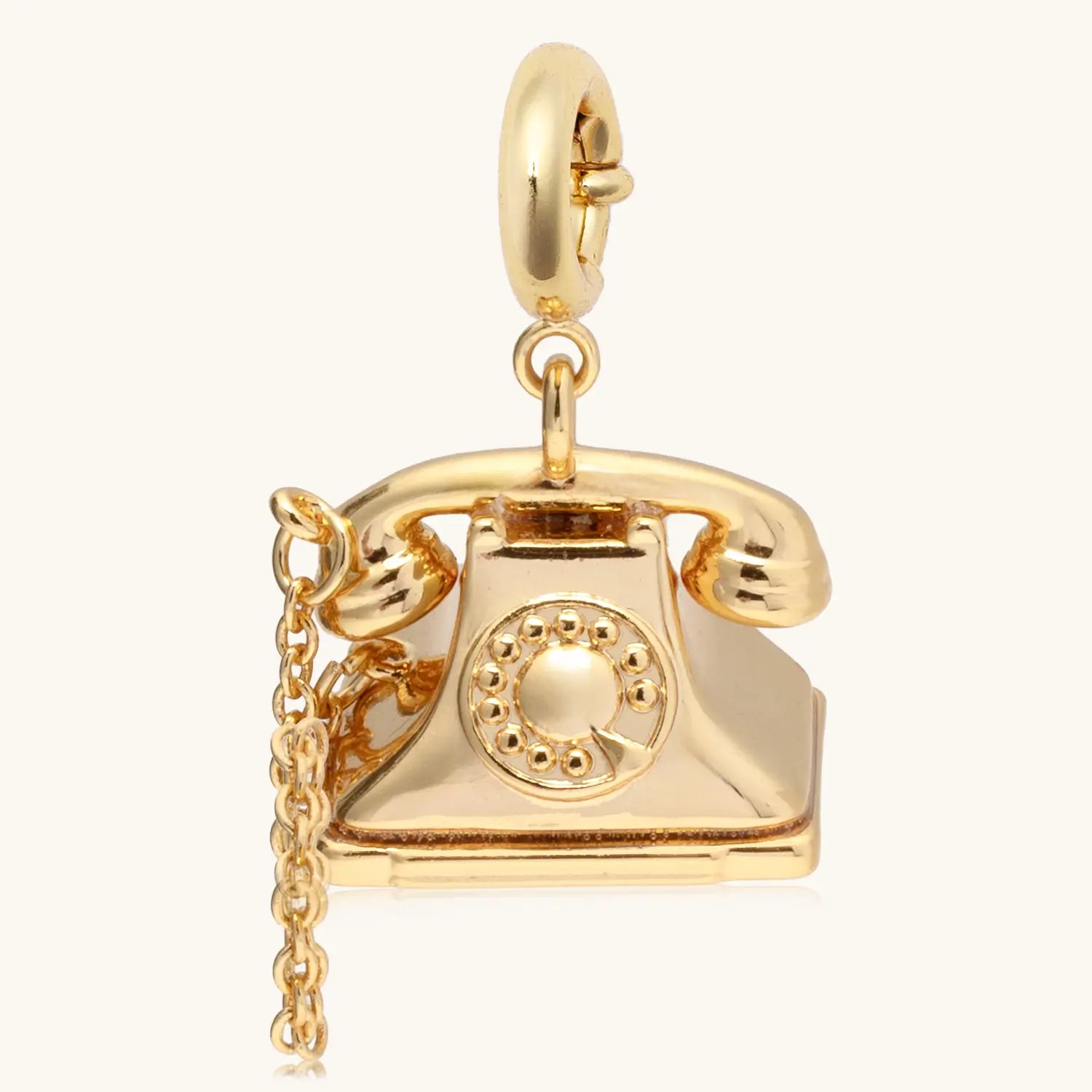Gold vintage rolling-dial telephone with a hanging chain suspended against a white background 