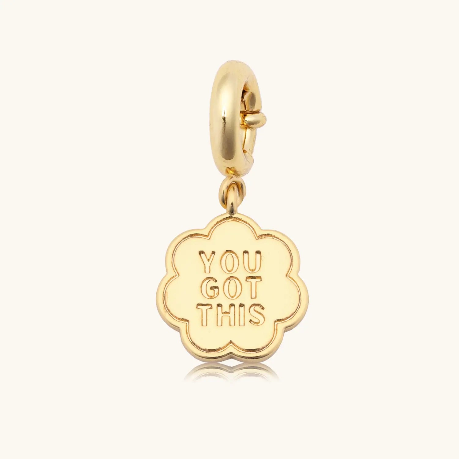 Gold floral shaped charm with text on body against a white background