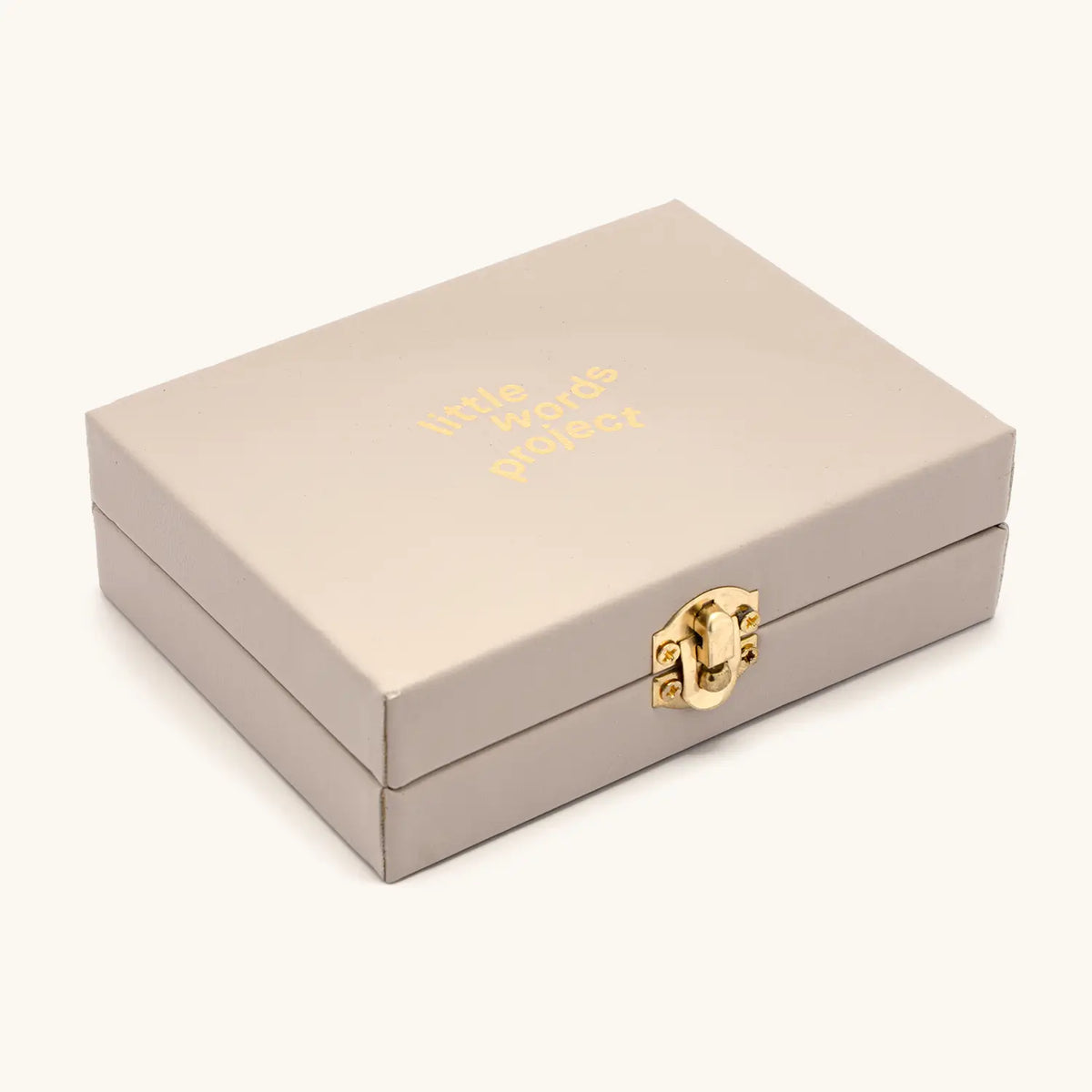Lariat Charm Set limited edition trunk box, taupe box with gold Little Words Project logo and gold latch, angled packaging shot on cream background