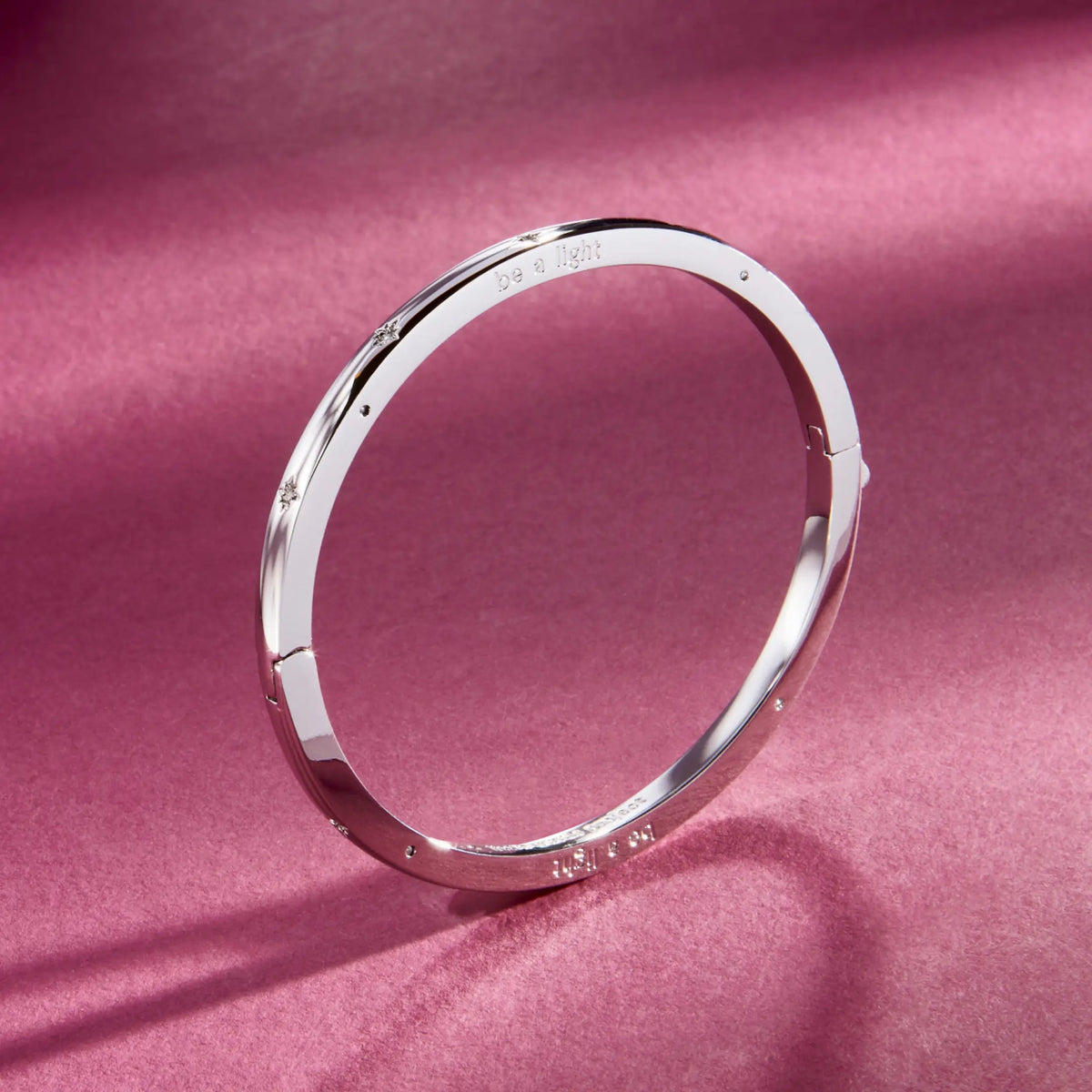 Be A Light Bangle, silver-plated bangle with CZ stone details and push button closure, detail on a berry background