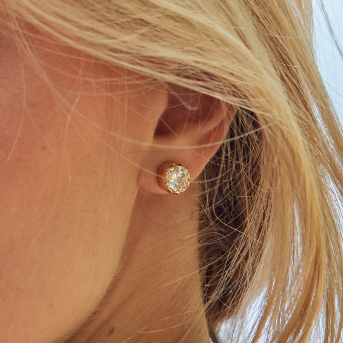 Breathe Scalloped Bezel Studs on-model, gold stud with a clear CZ stone in a scalloped bezel