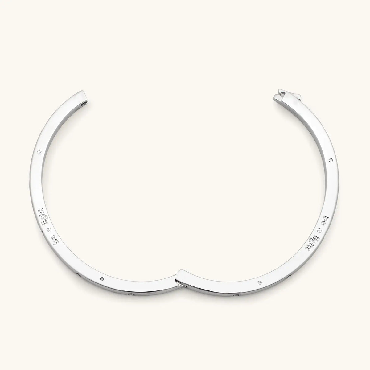 Be A Light Bangle open, silver-plated hinged bangle showing be a light engraved on the inside, detail on cream background