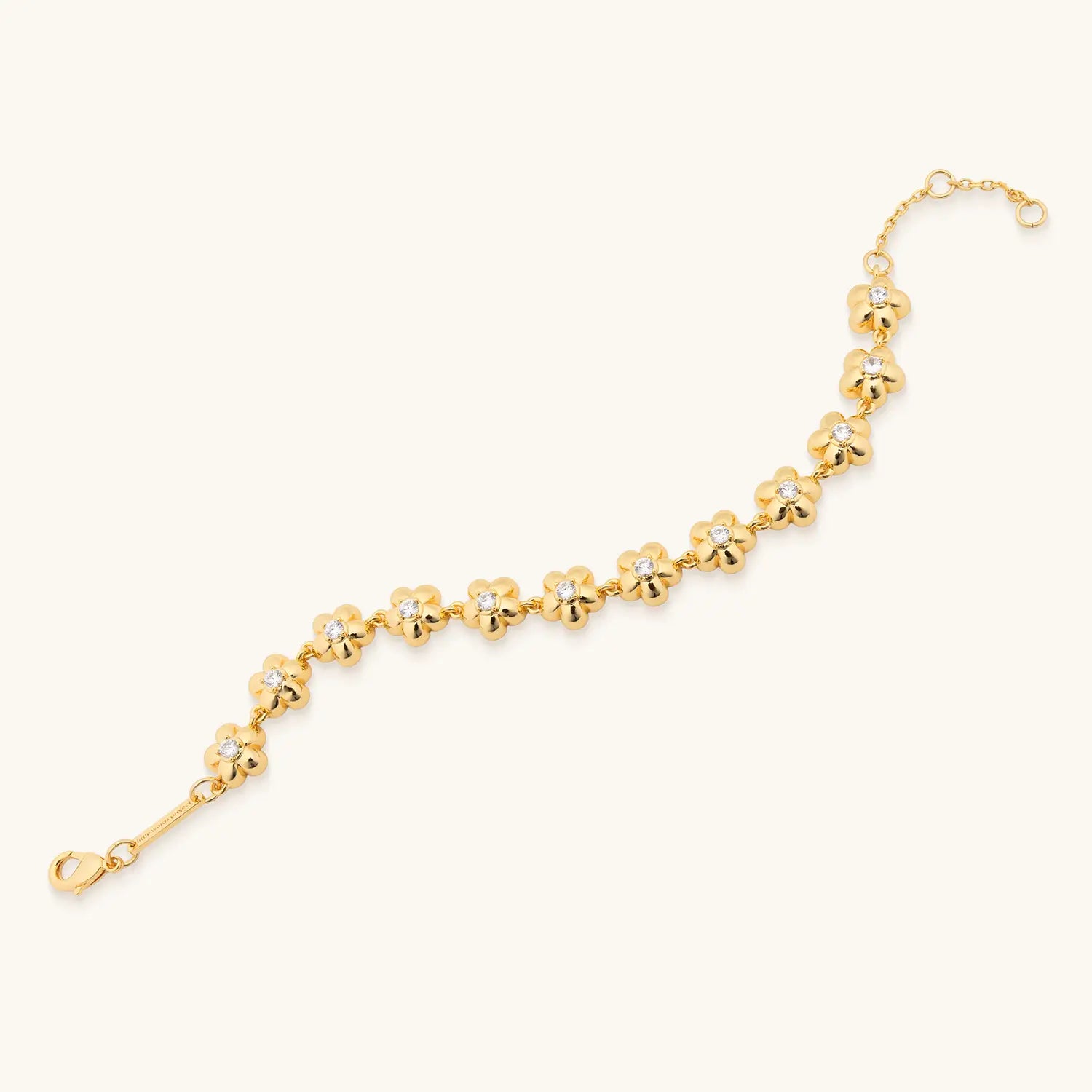 Gold bracelet with a delicate chain of small, polished flower-shaped links, each centered with a tiny clear gemstone, arranged in a gentle curve on a plain light background.