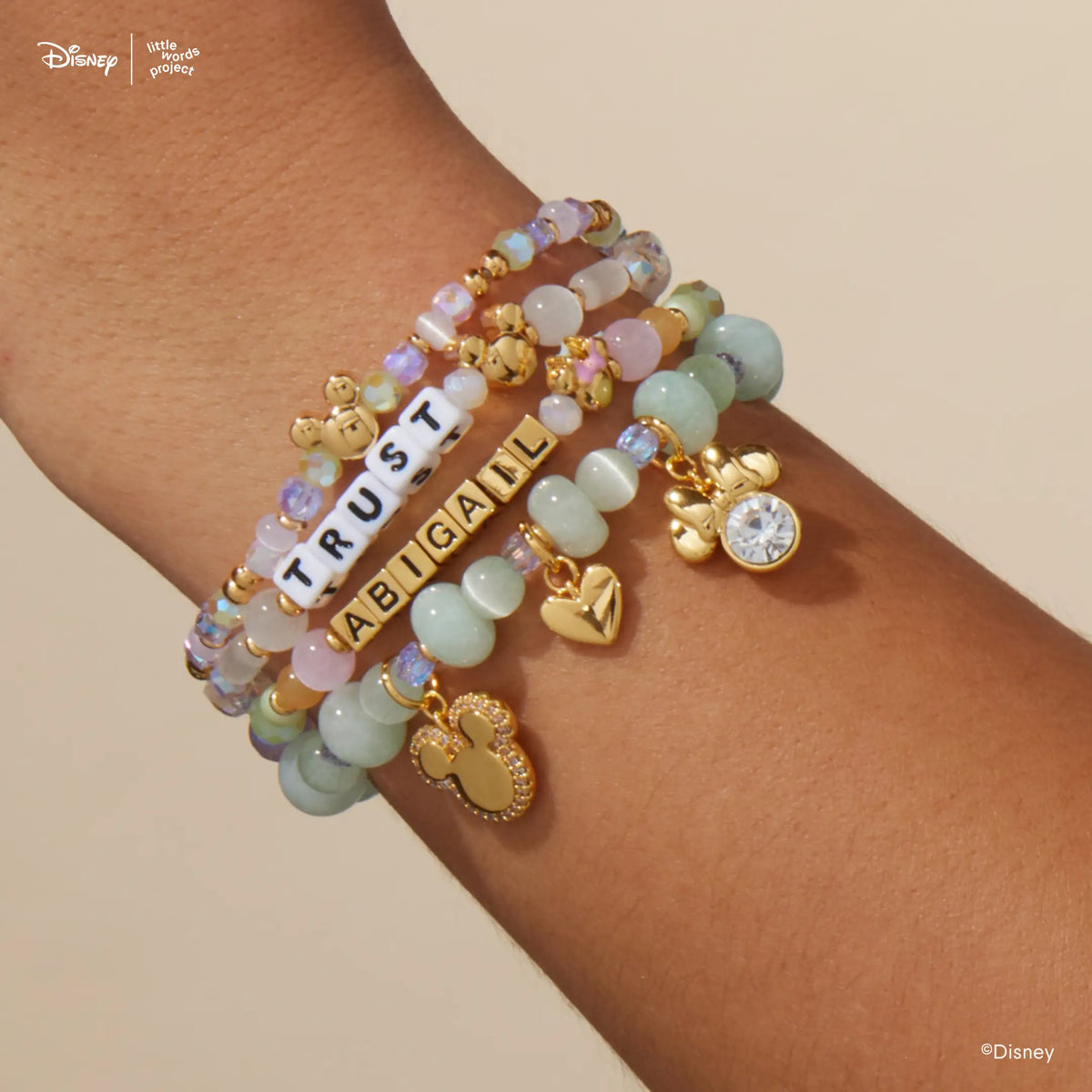 Disney Mickey & Friends custom bracelets stacked on wrist with Mickey Custom Magic Maker and Minnie Custom Dot Darling, pastel and white beads with gold Mickey Mouse and Minnie Mouse beads