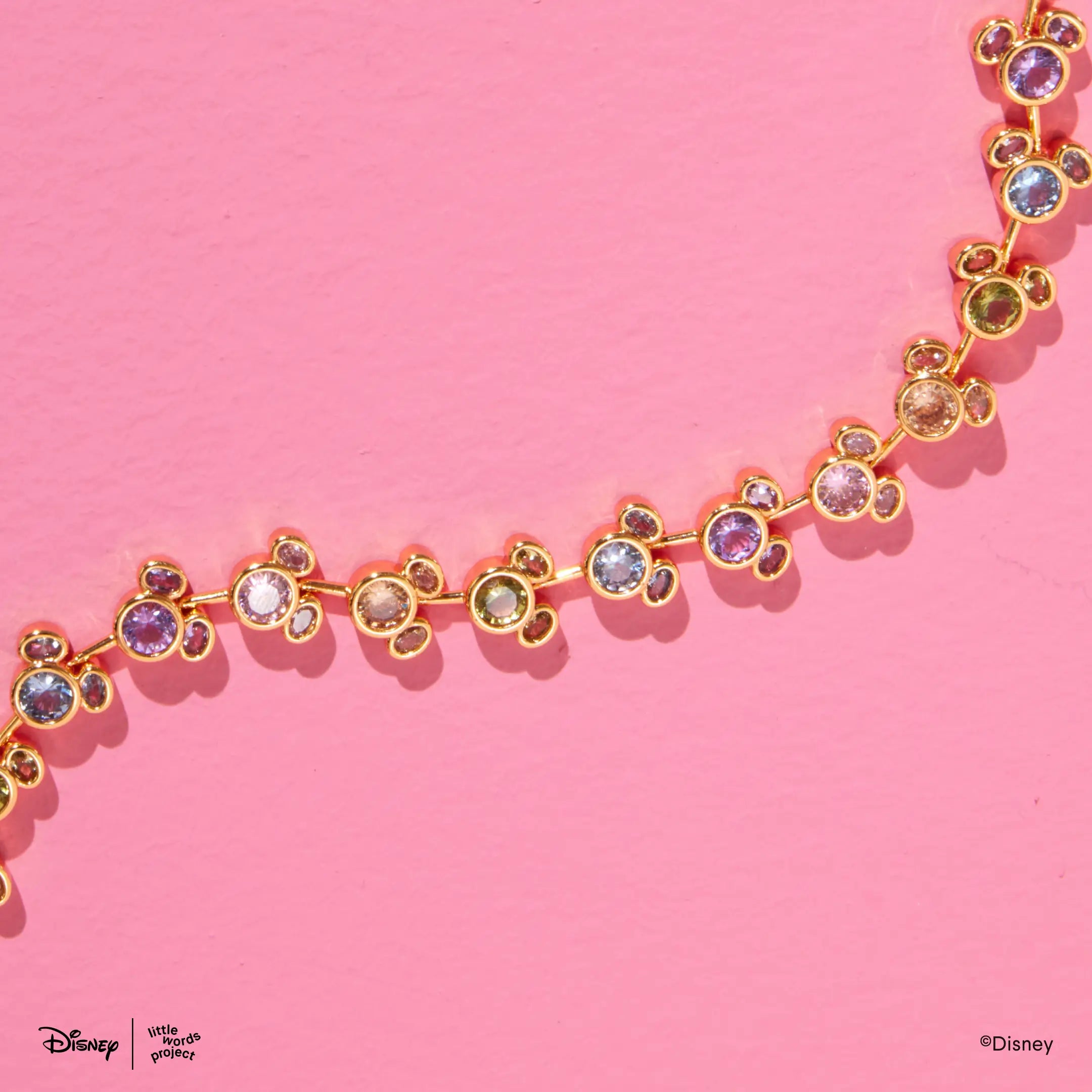 Mickey Mouse Rainbow Bracelet from Disney Mickey and Friends on pink, close up of the gold plated Mickey Mouse links set with multicolor crystals