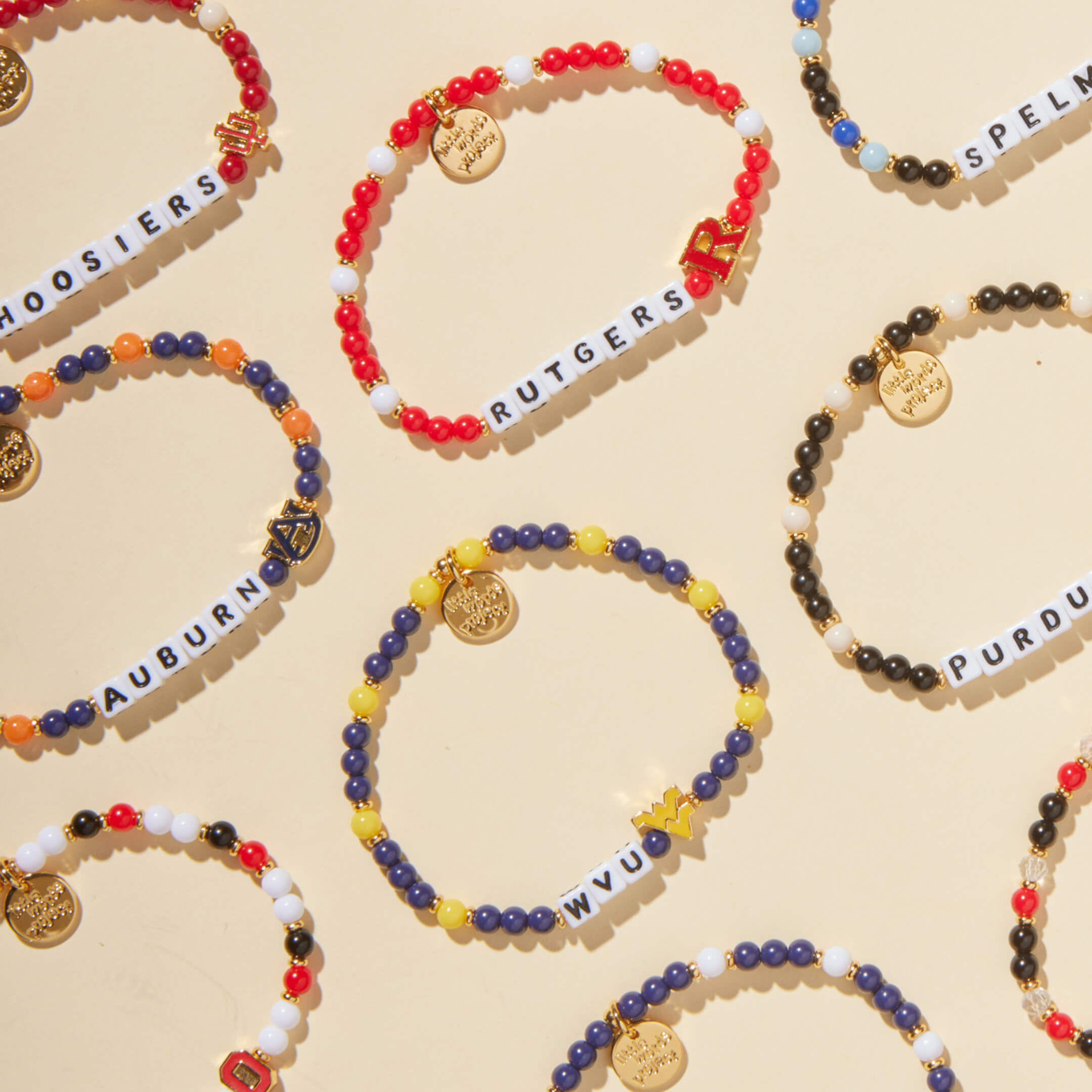 Colorful beaded bracelets with letter charms on a beige background