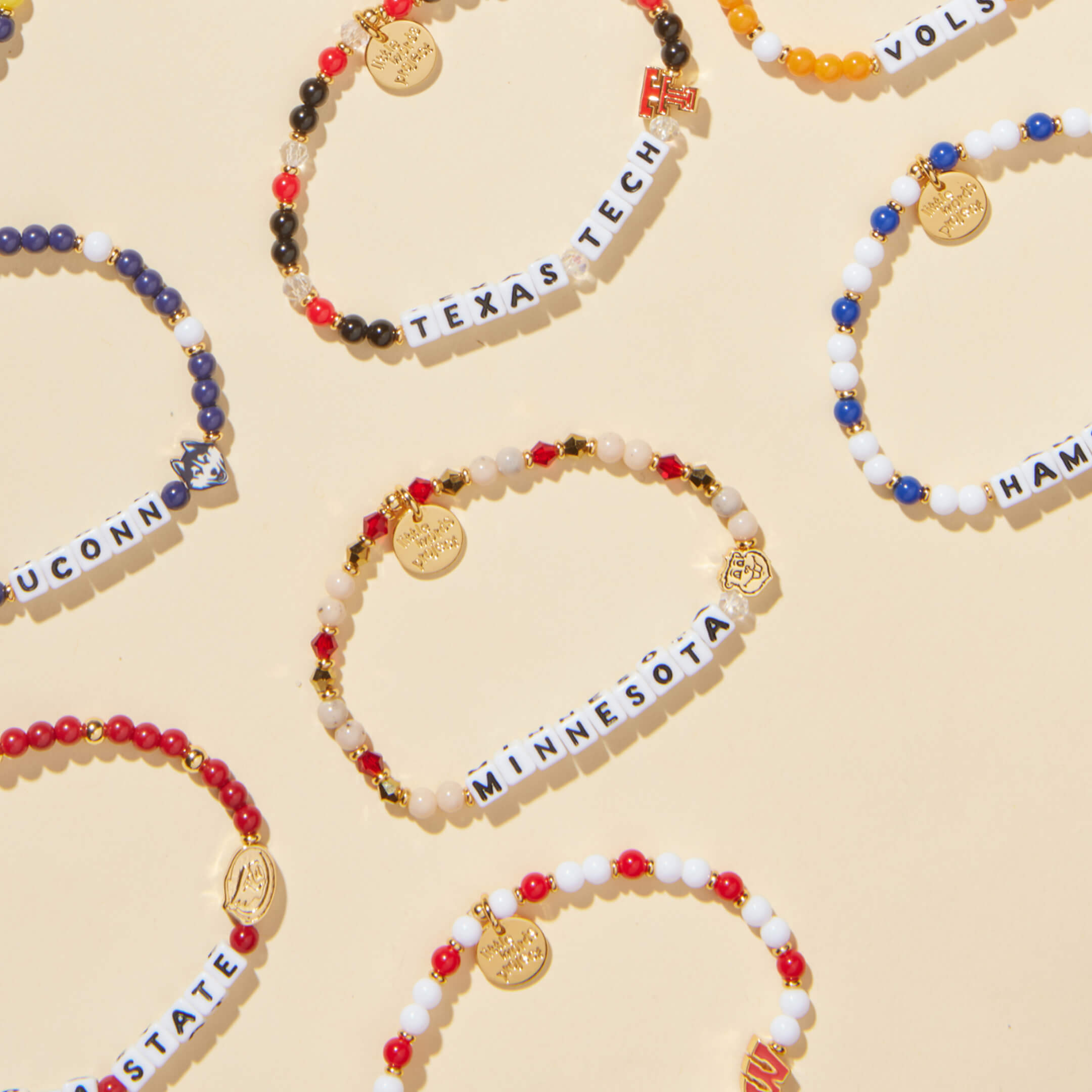 Beaded bracelets with letter tiles spelling out names on a beige background