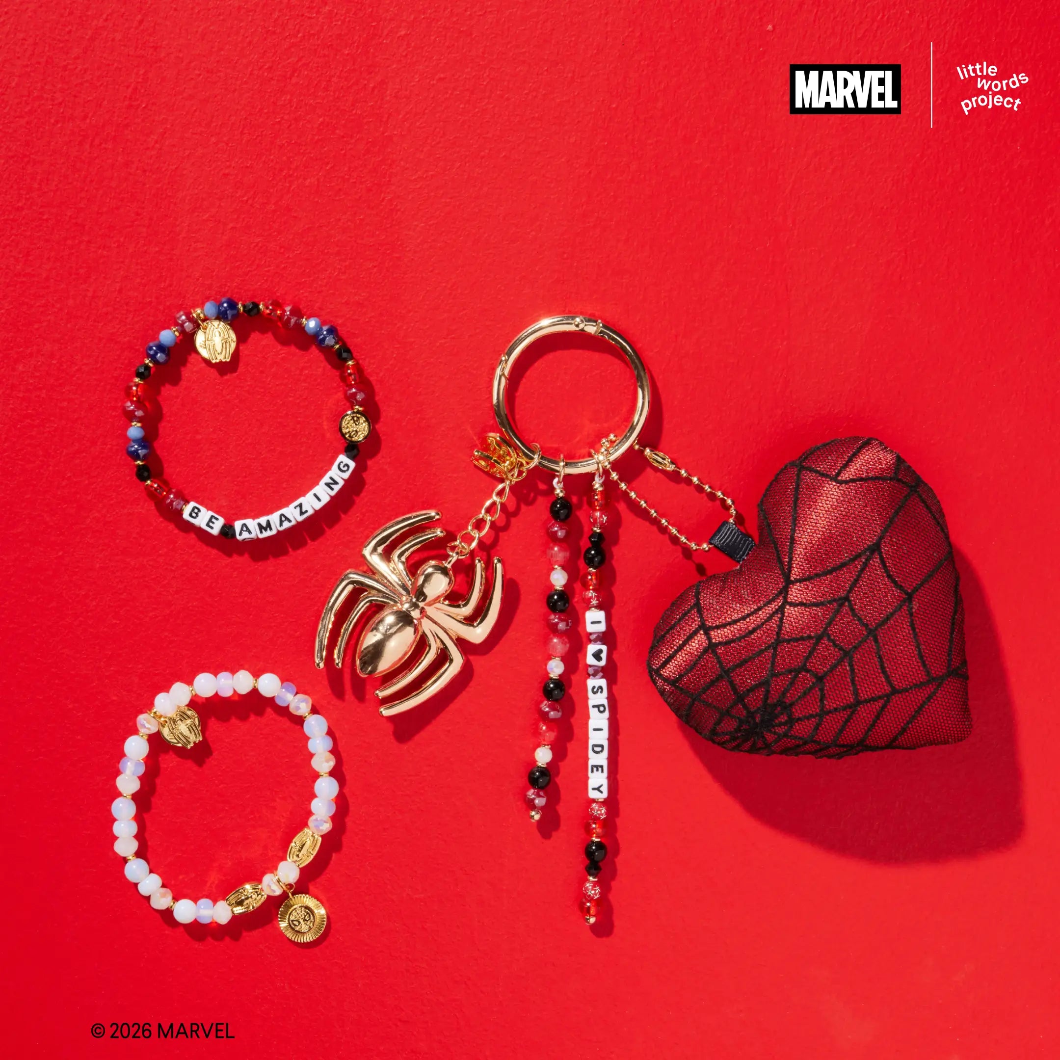 Friendly Neighborhood Faves Set from Marvel's Spider-Man collection, flat-lay on red background showing Be Amazing bracelet, Power Brings Responsibility Bracelet Base, and I Heart Spidey Bag Charm