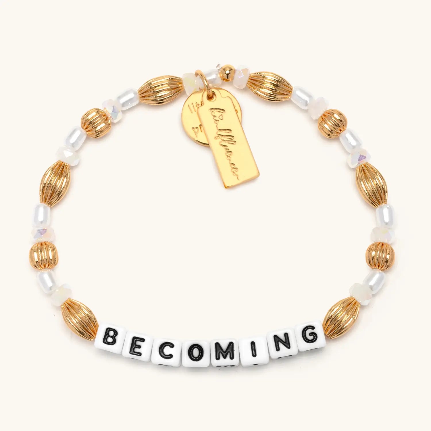 Becoming- Nika Diwa bracelet flat-lay, gold plated brass oval beads, faux pearls, opalescent stone beads, gold Nika Diwa tag charm