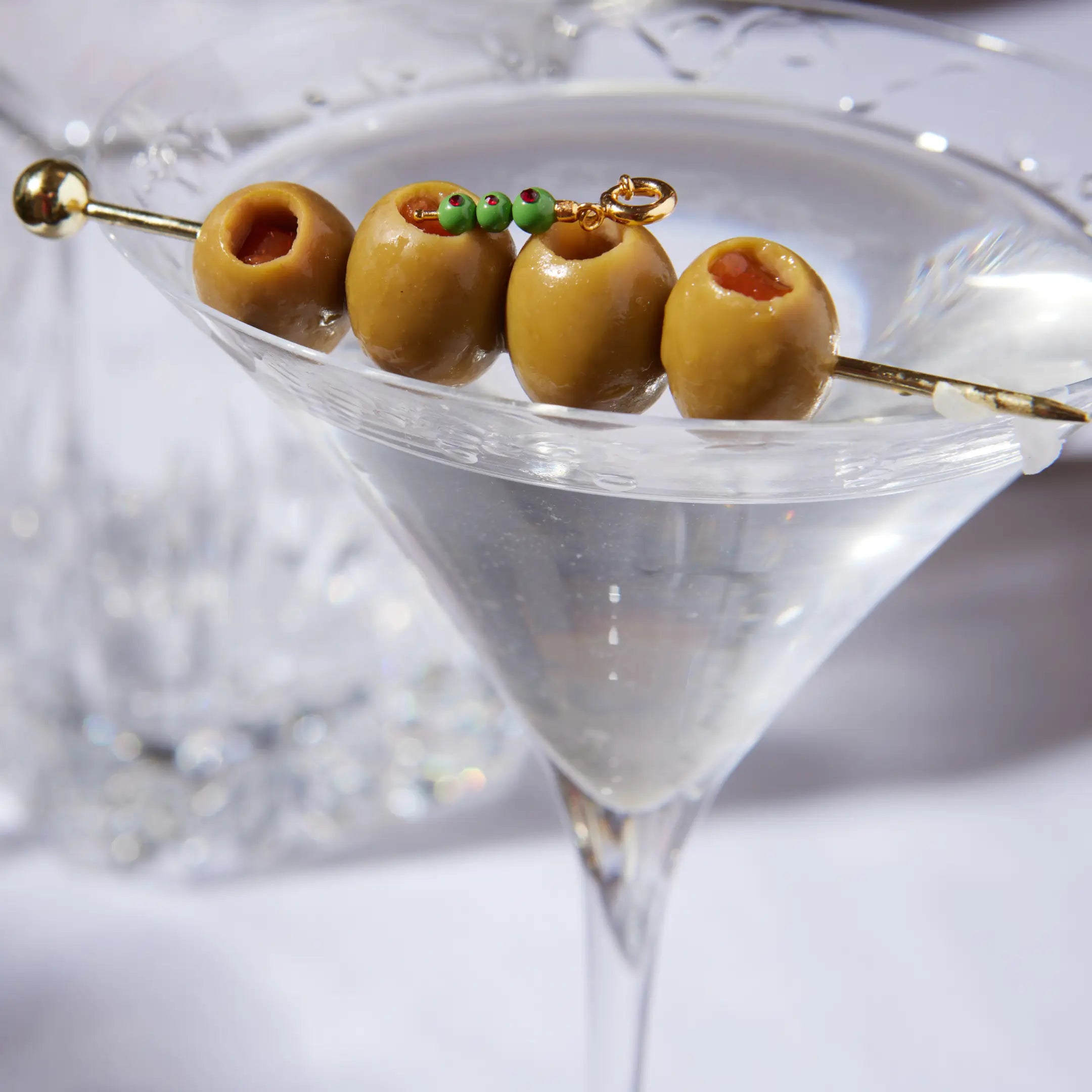 Martini glass with olives on a skewer against a blurred background