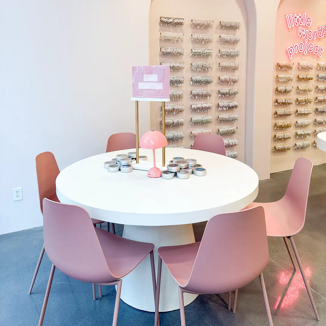 Round white table with pink chairs in a room with decorative wall art.