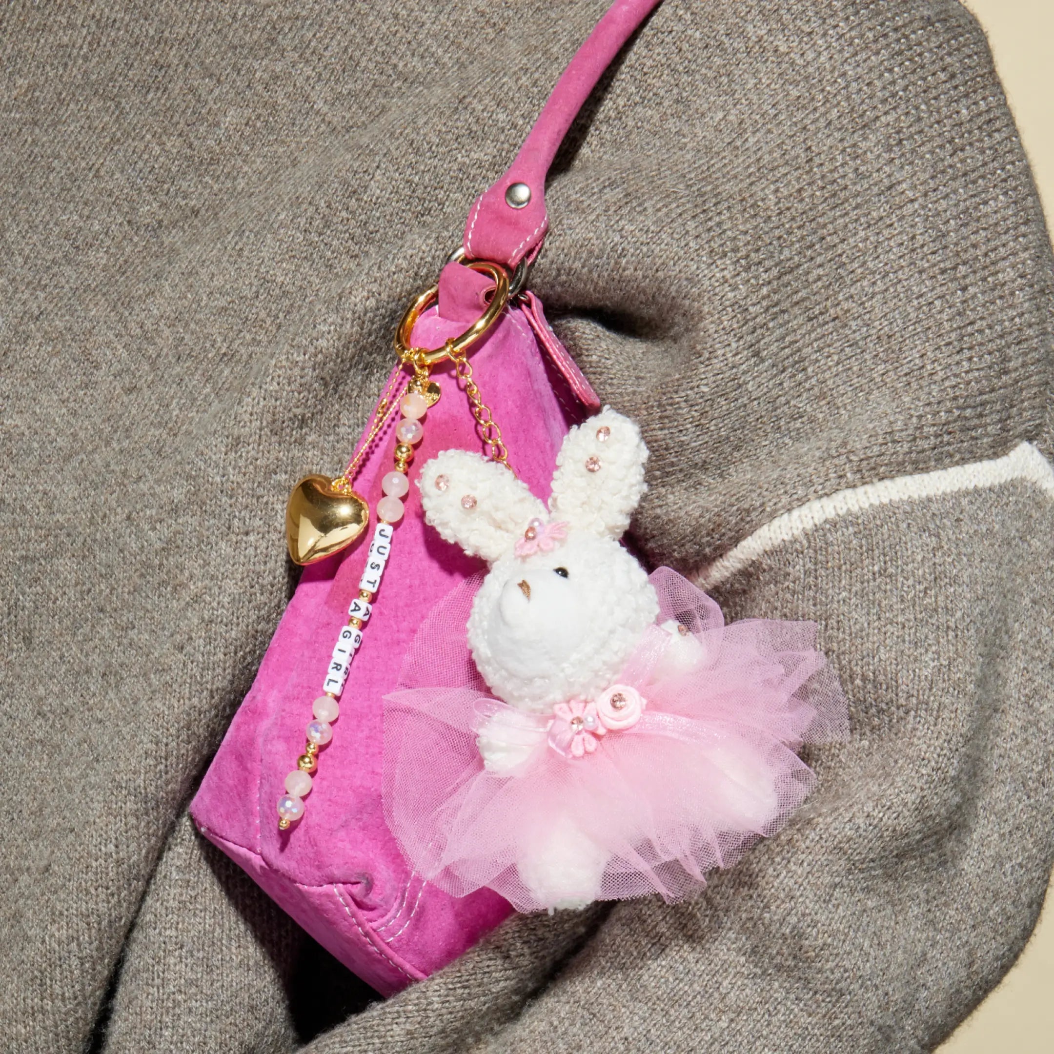 Pink handbag with a white rabbit keychain on a textured surface