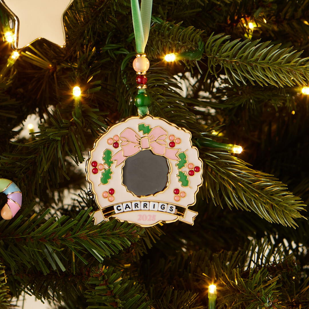 Decorative Christmas ornament with 'CARRIGS' on a lit Christmas tree.