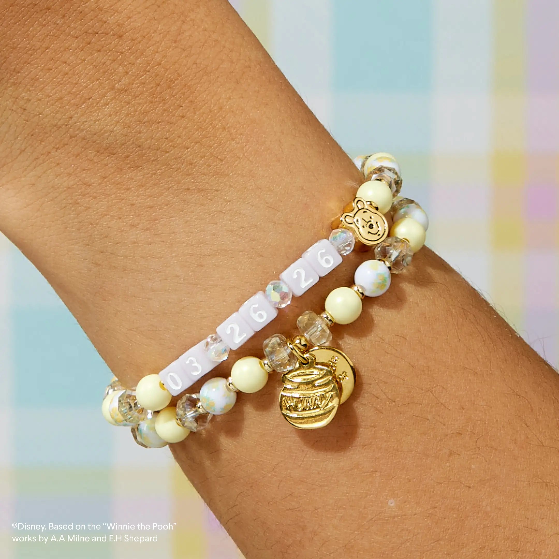 Beaded bracelet with a gold tag on a wrist against a colorful background