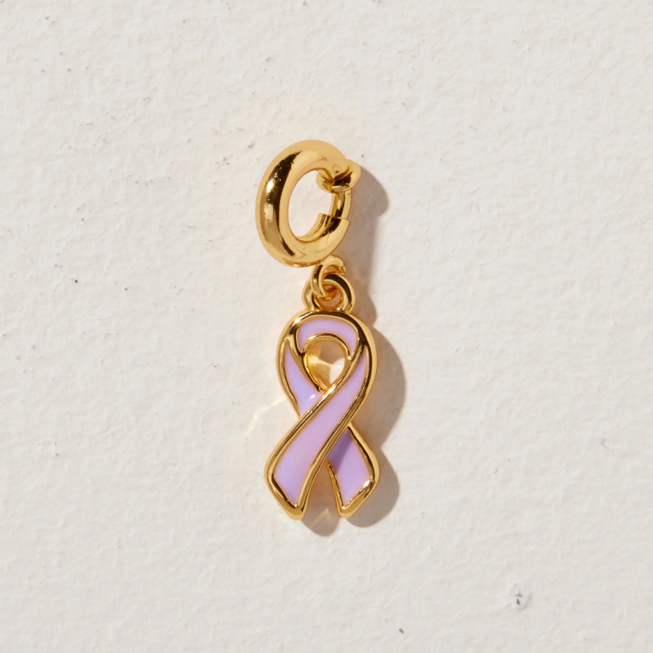 Gold charm with a purple ribbon on a light beige background