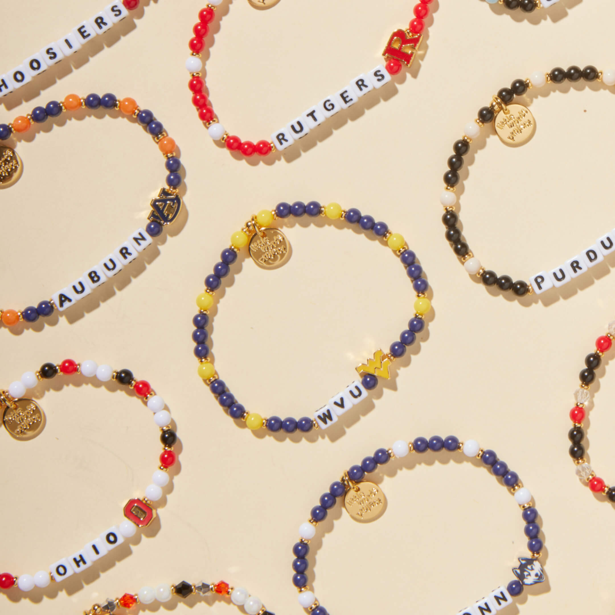 Colorful beaded bracelets with team names on a beige background