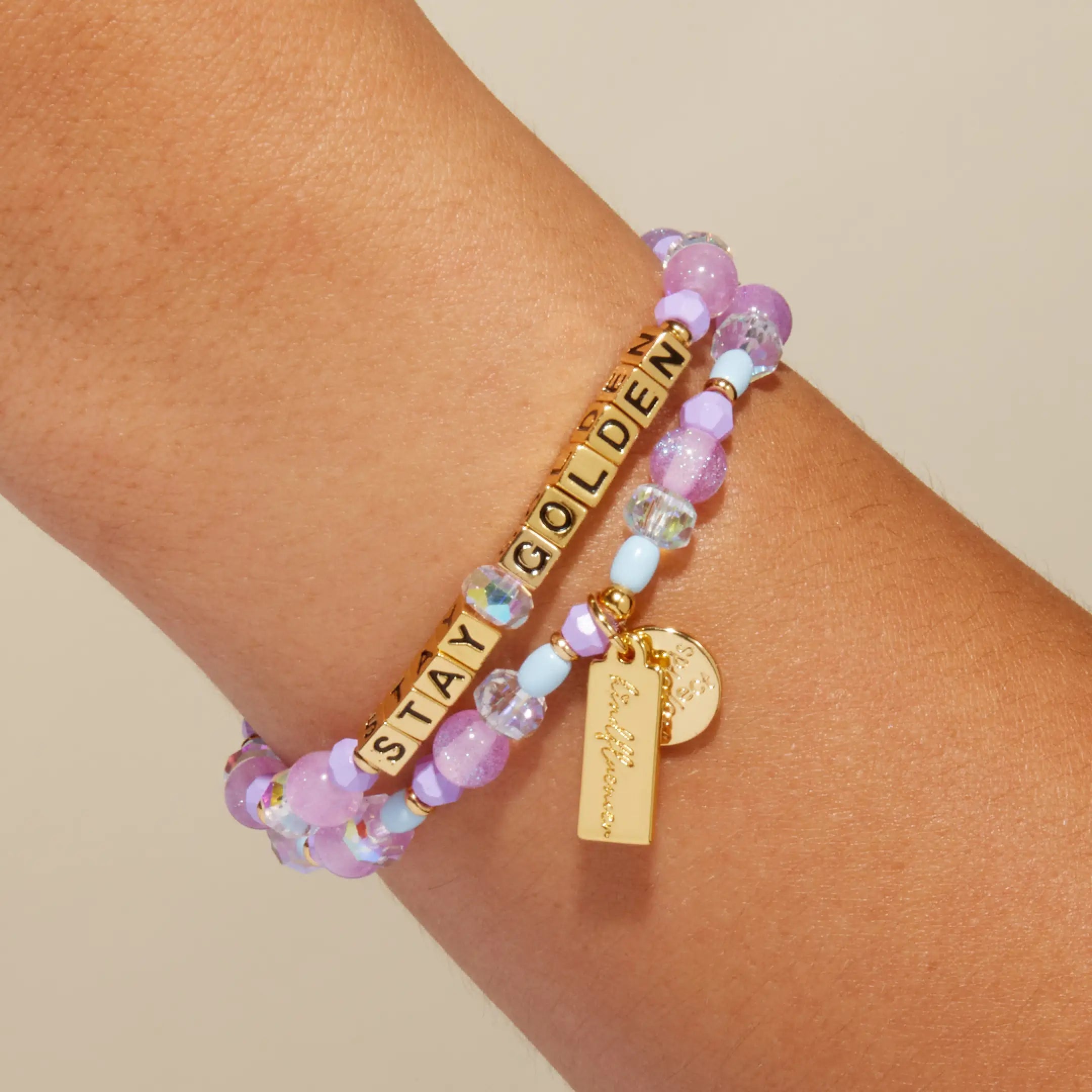 Stay Golden Rylee Ta bracelet with gold letter beads and lavender crystal beads worn on a wrist, on-model close up
