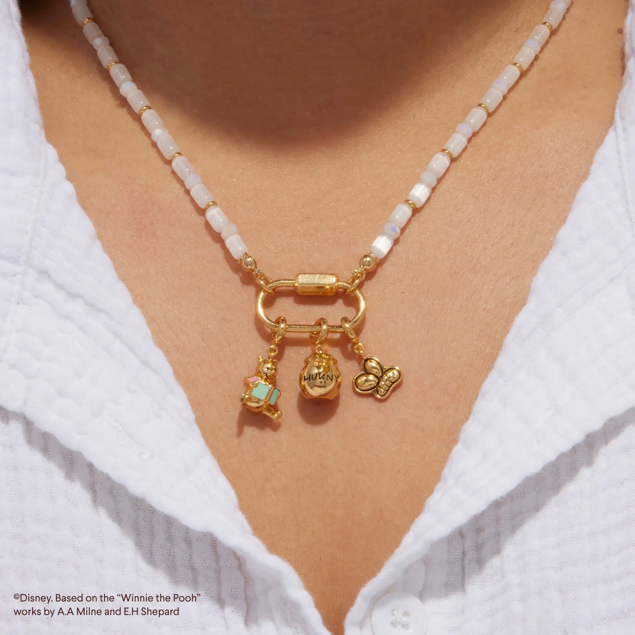 Necklace with gold clasp and charms on a white shirt
