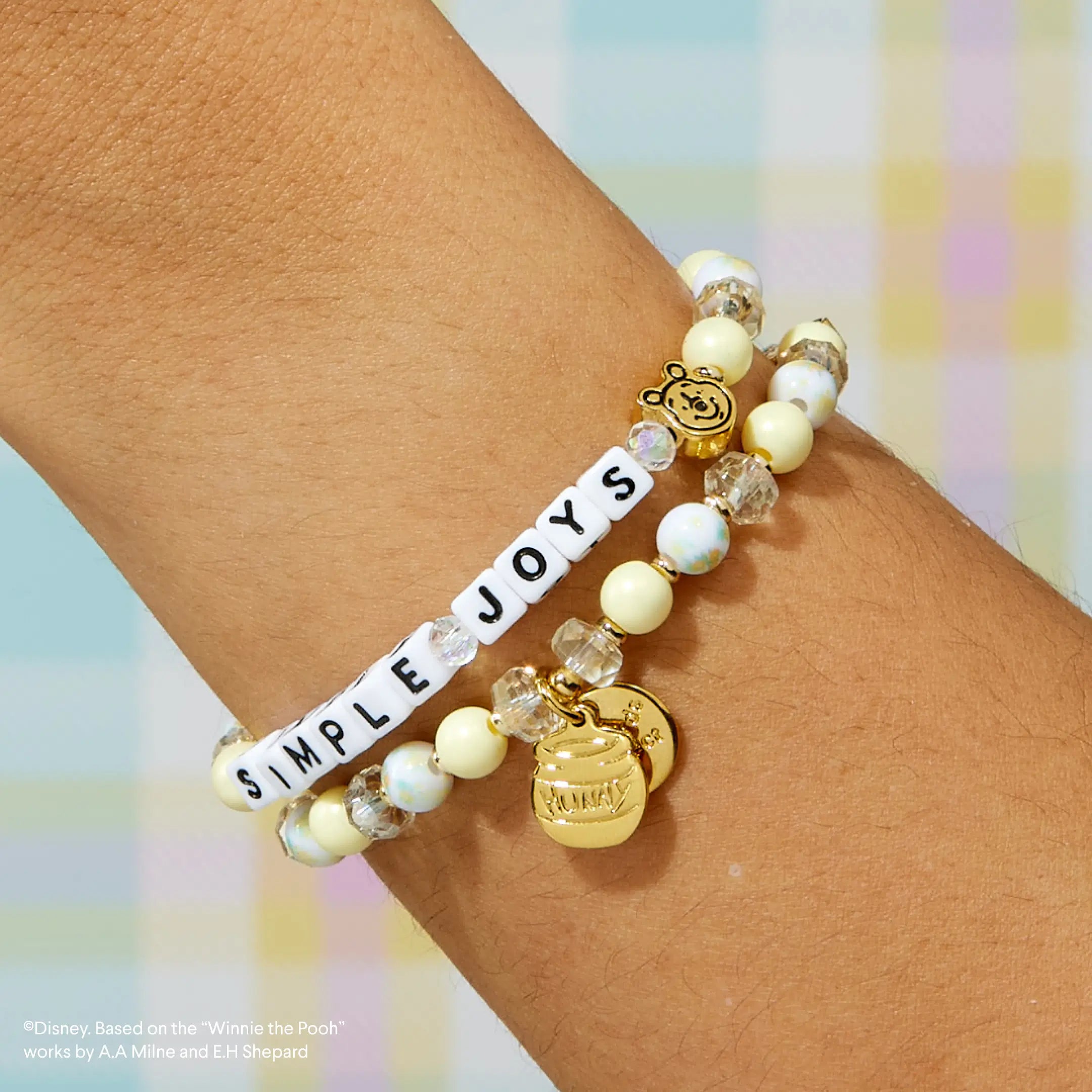 Bracelet with 'Simple Joys' on a wrist against a colorful background
