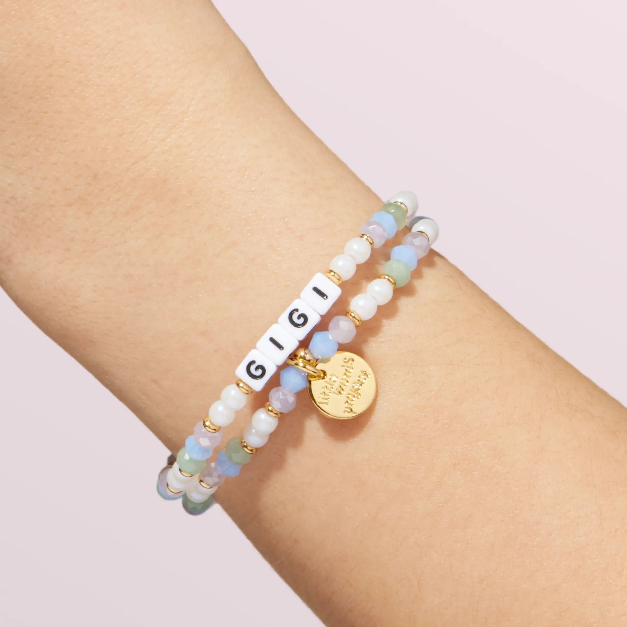 Multicolored beaded bracelet with a gold tag on a wrist against a light background
