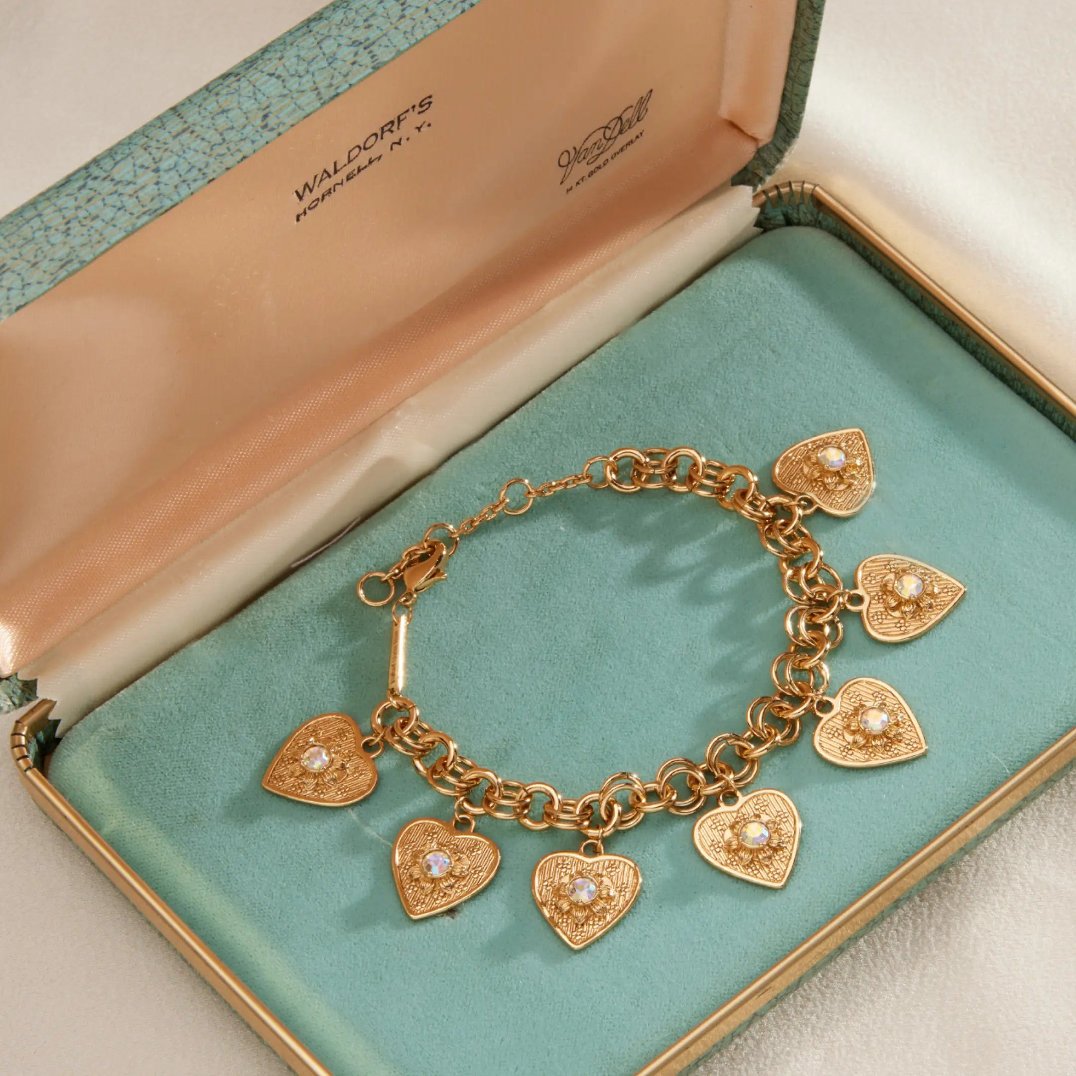 Gold bracelet with heart-shaped charms in a jewelry box