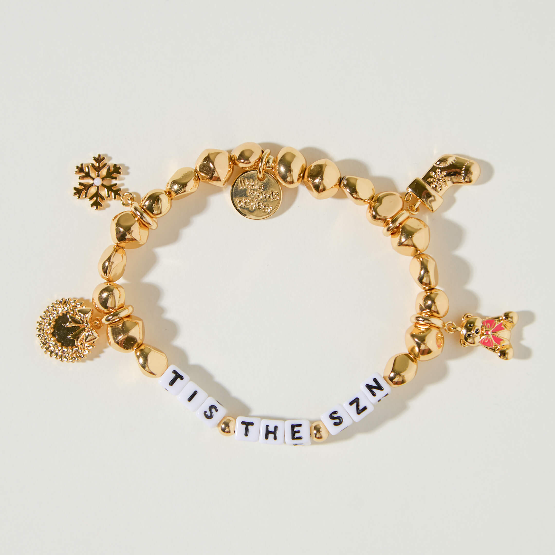 Gold bracelet with festive charms on a light background