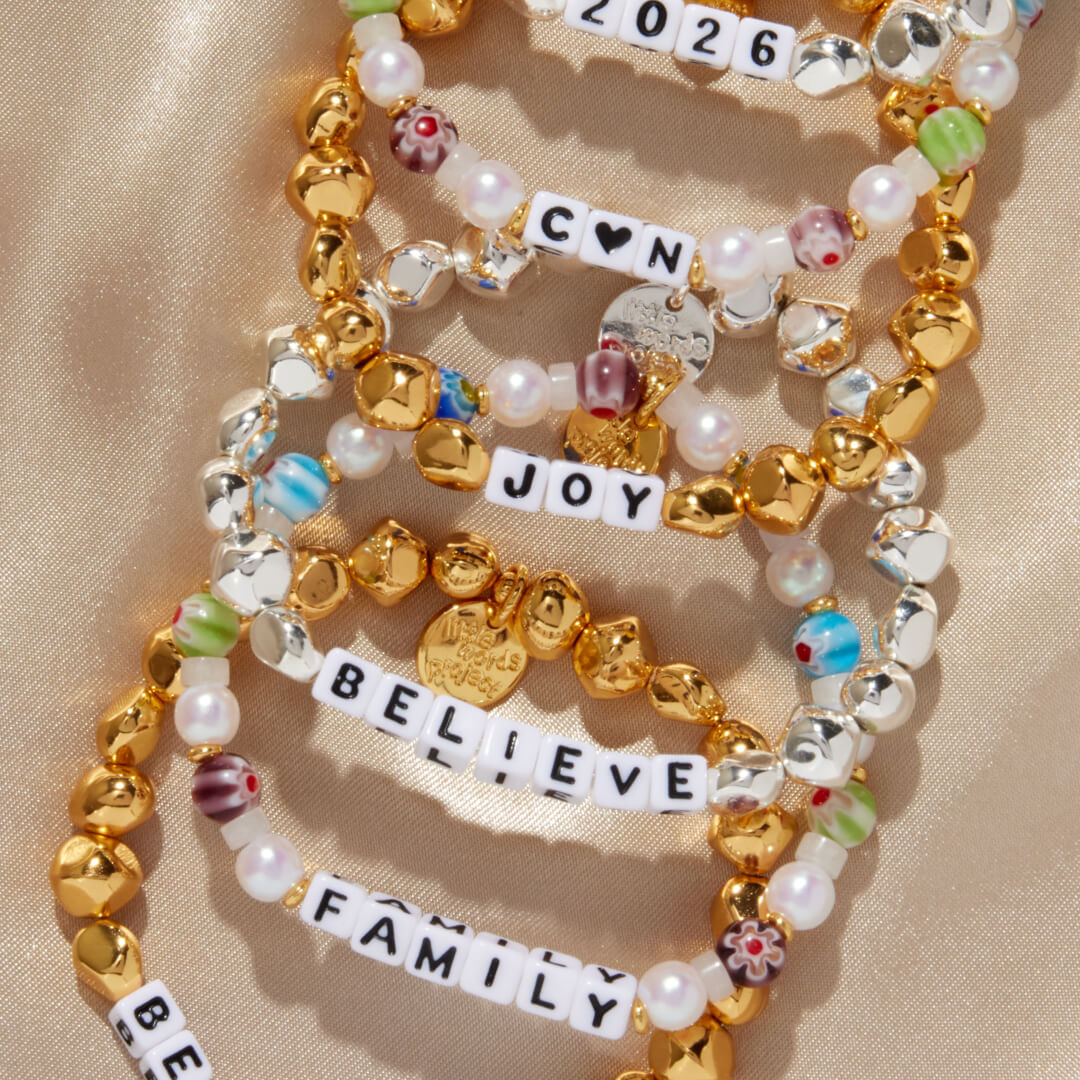 Stack of colorful beaded bracelets with inspirational text on a beige background