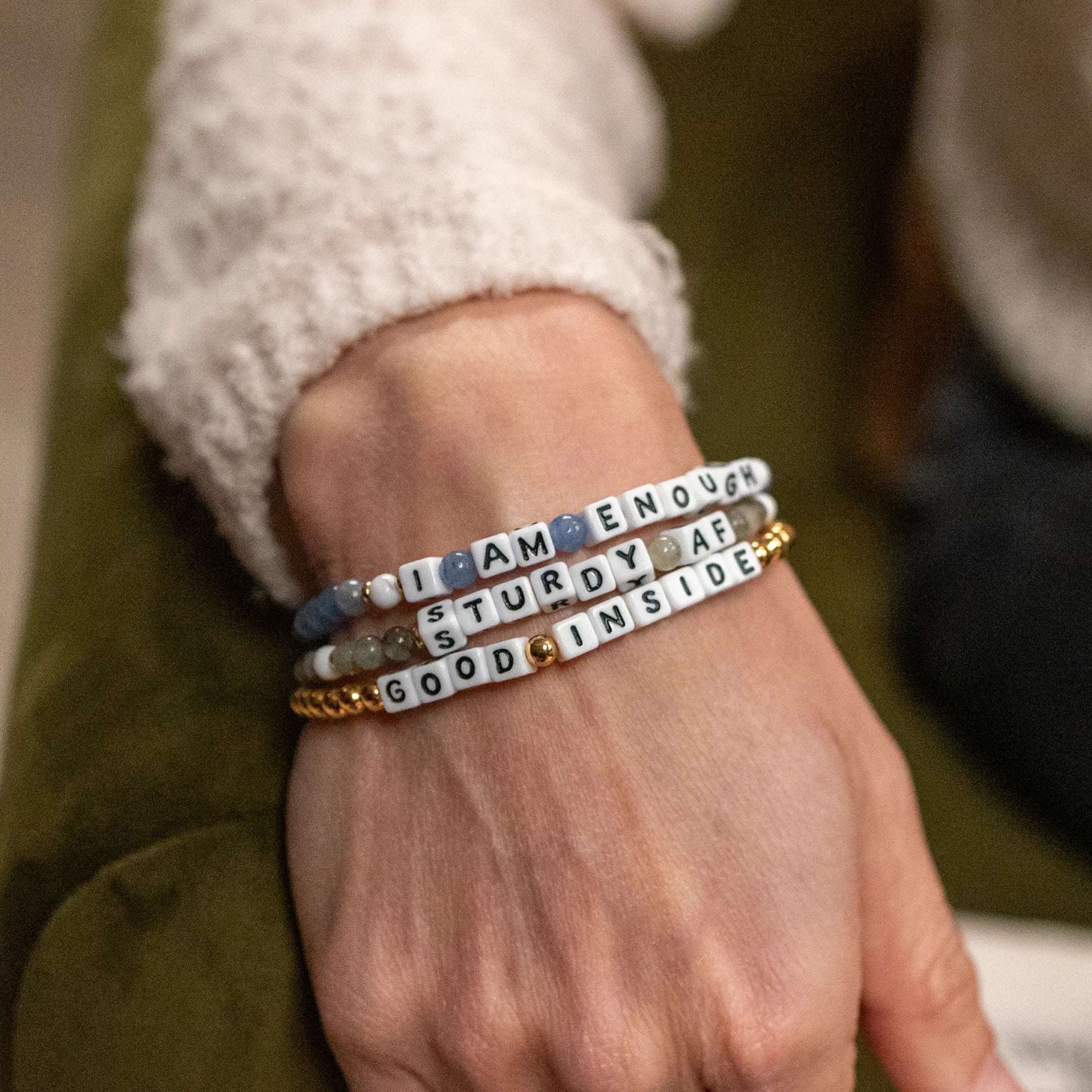 Bracelets with motivational phrases on a wrist against a blurred background
