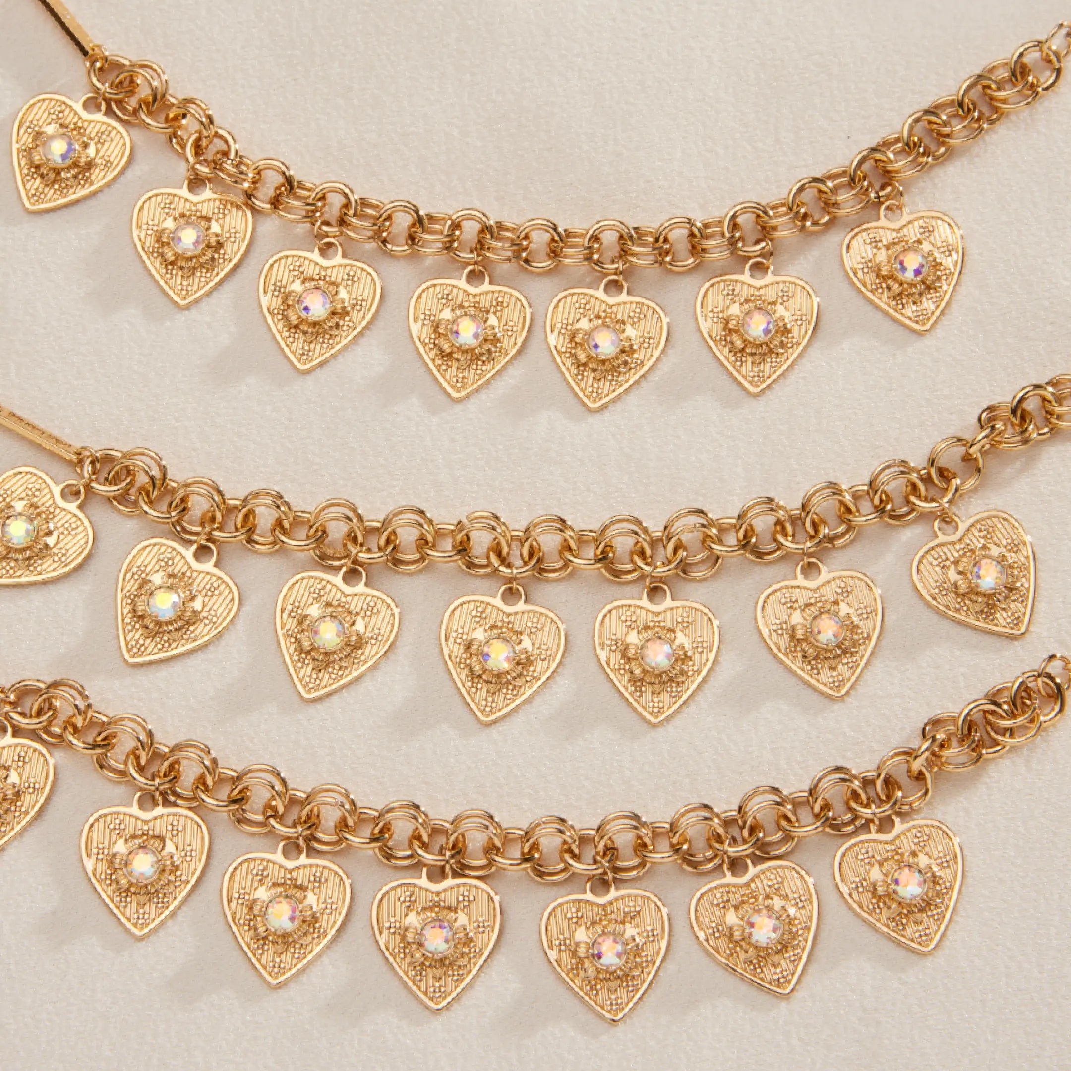 Gold heart-shaped charm bracelets on a light background